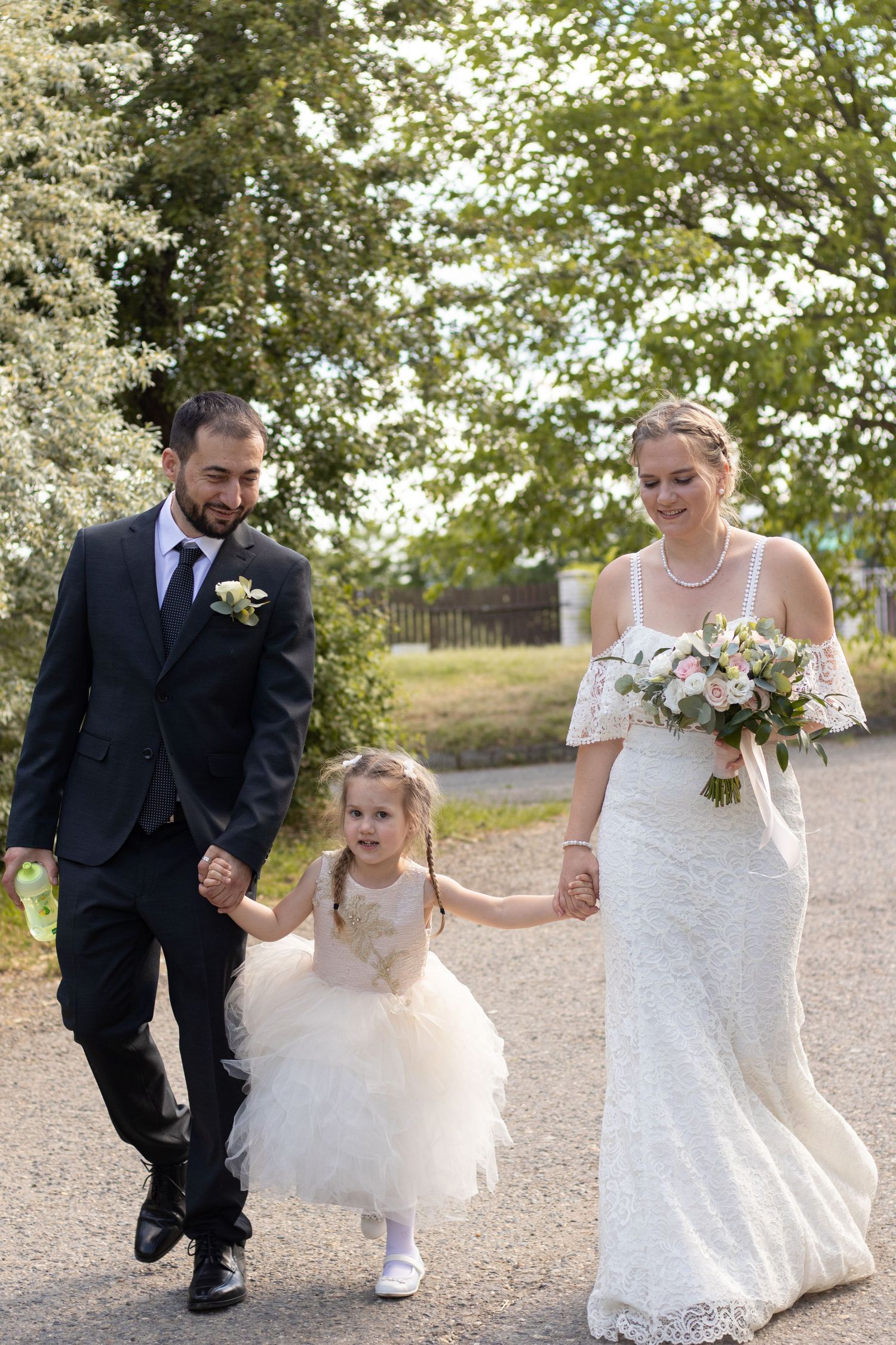 Joyful moment captured on a tree-lined path during a wedding celebration.