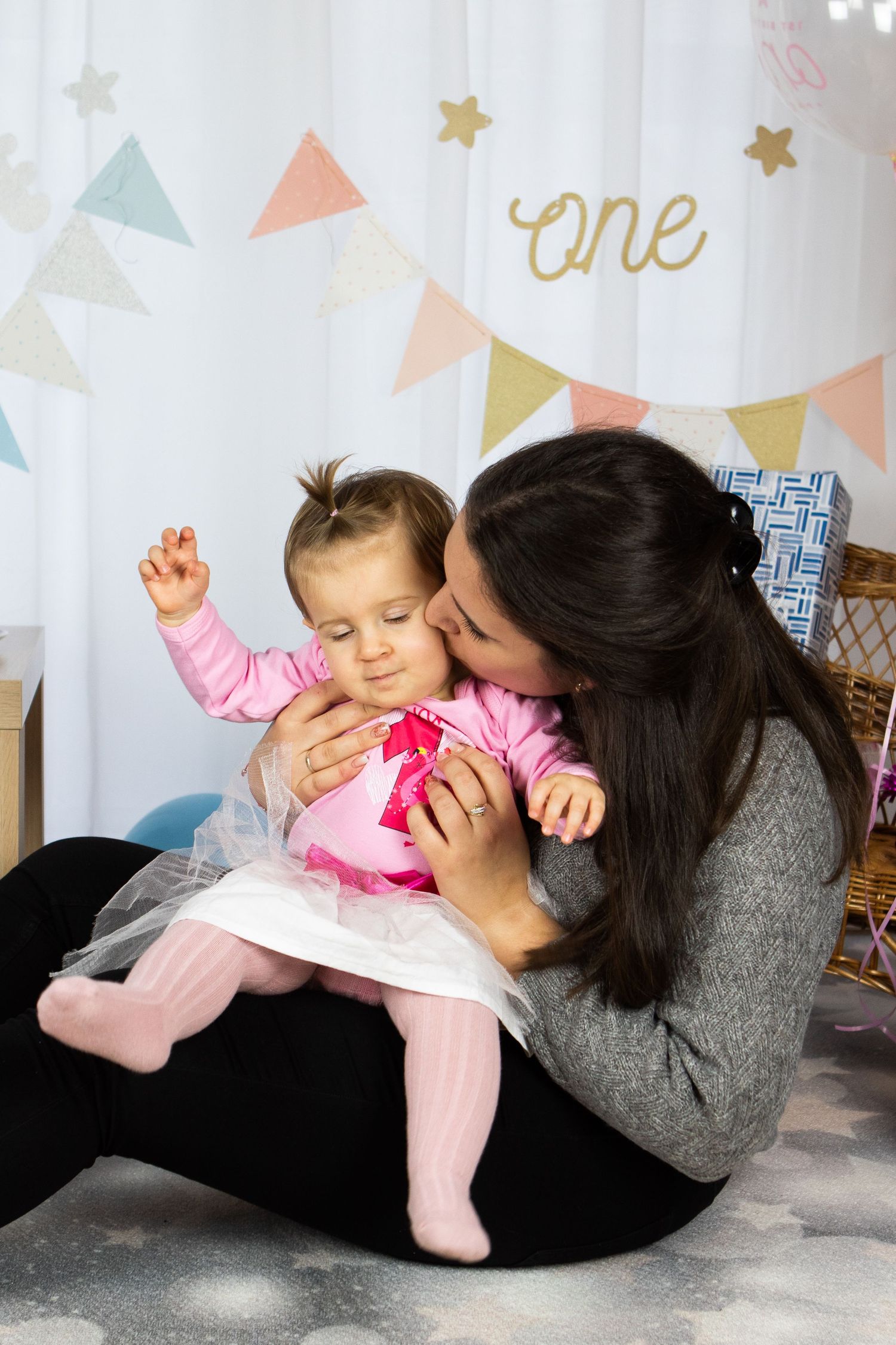 Playful indoor photoshoot with pink decorations and party bunting backdrop.