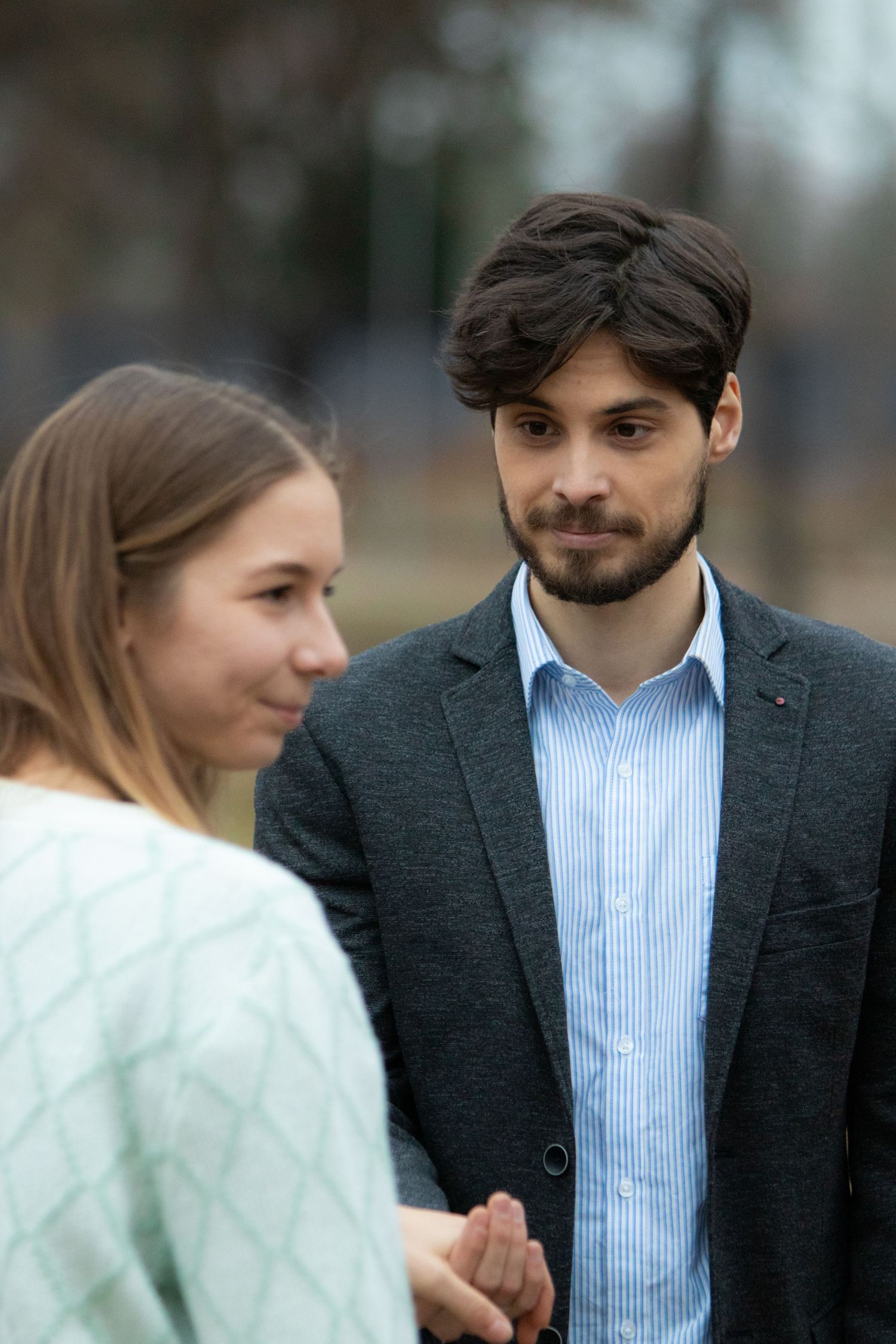 A couple in formal wear shares romantic glances during an outdoor photoshoot.