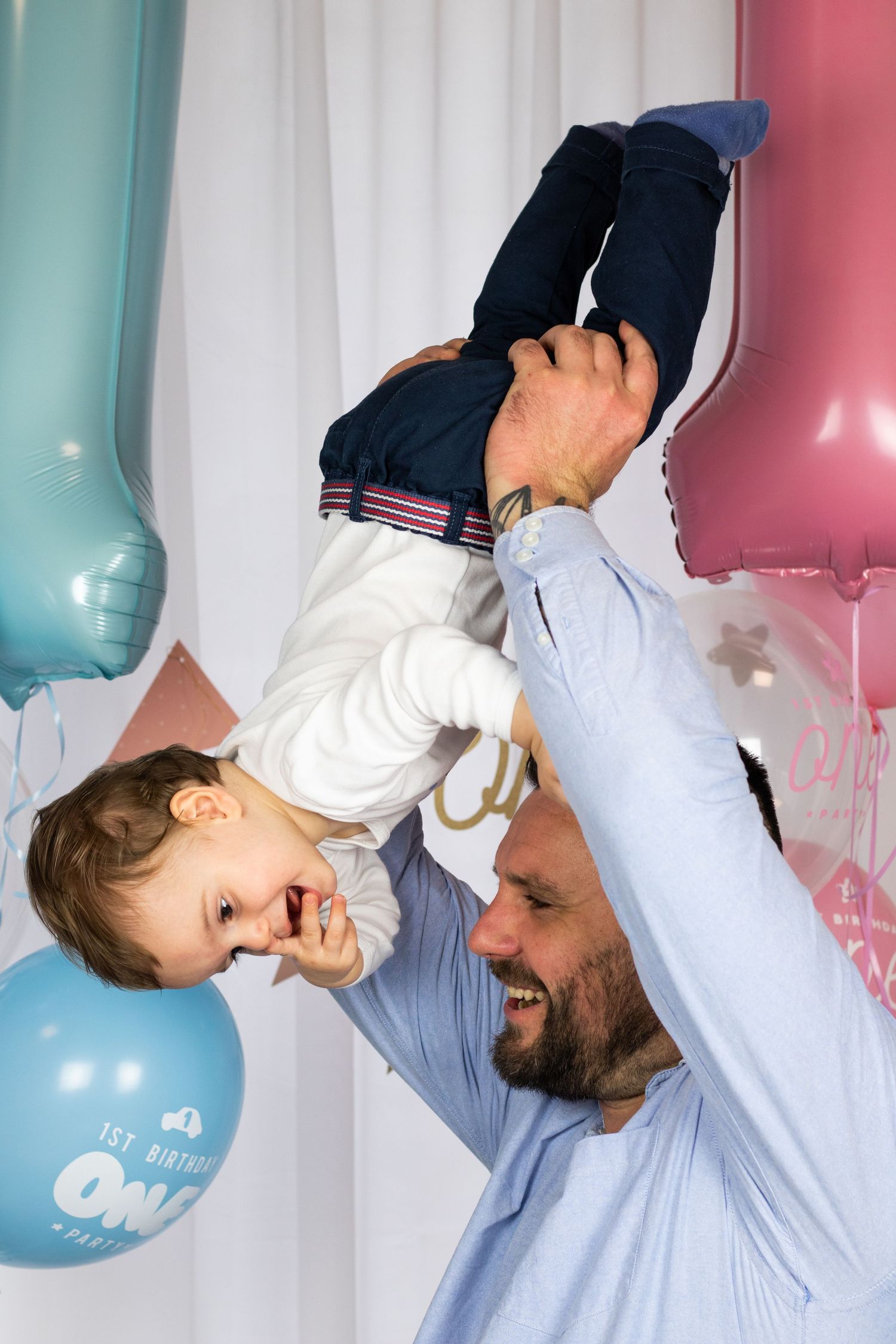 Playful indoor photoshoot with blue and pink balloon decorations.