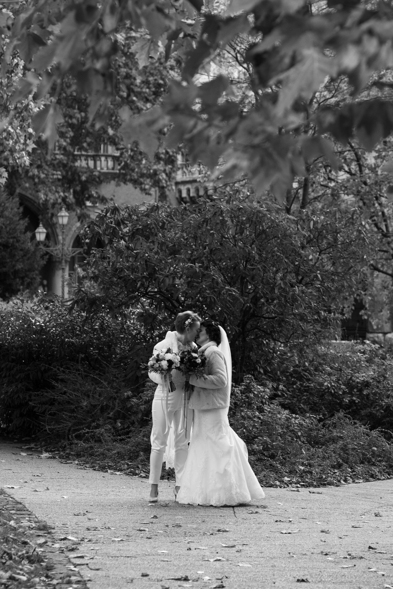 Black and white wedding photography of couple walking through garden path.