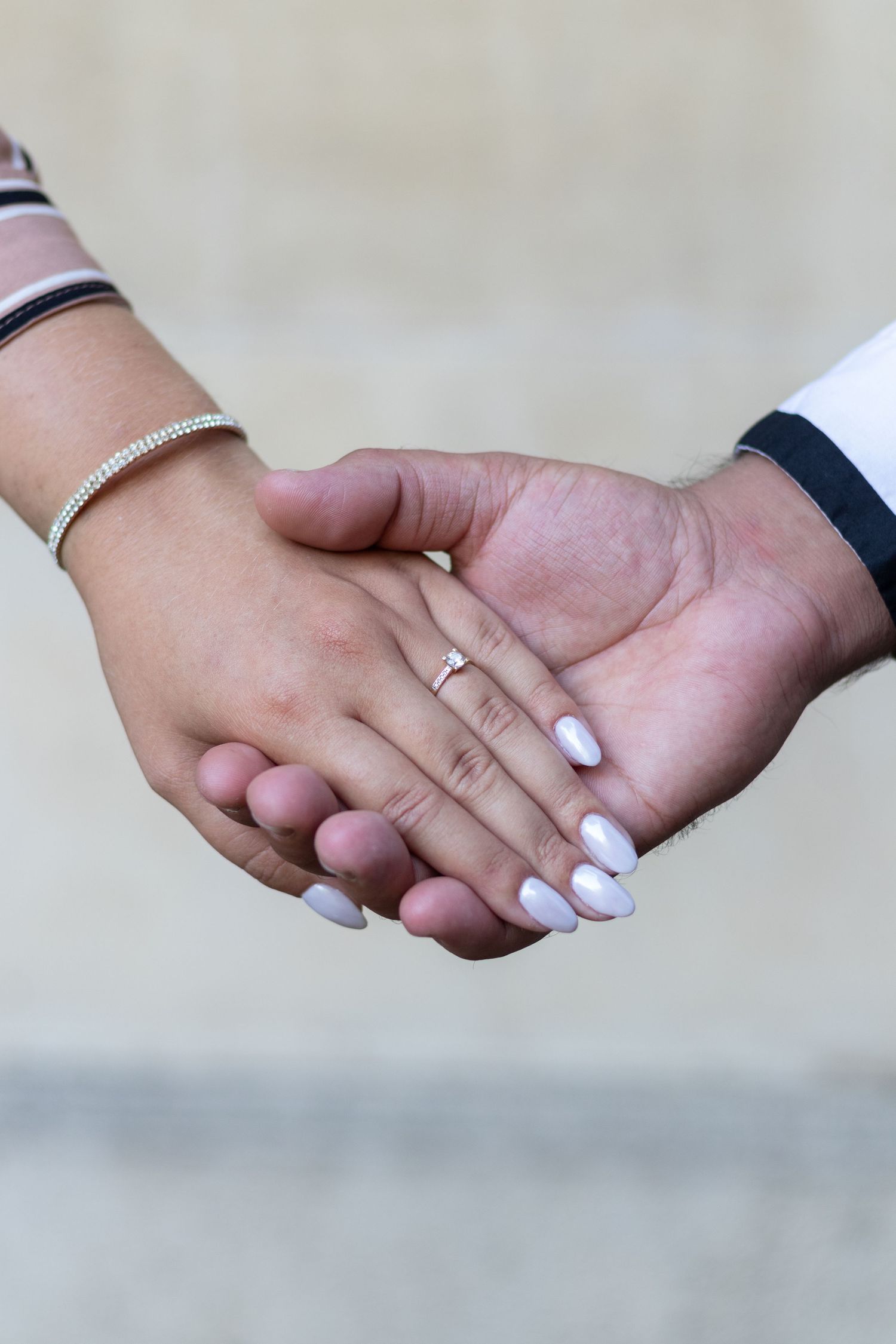 Close-up shots of hands holding each other showing wedding rings and manicured nails.