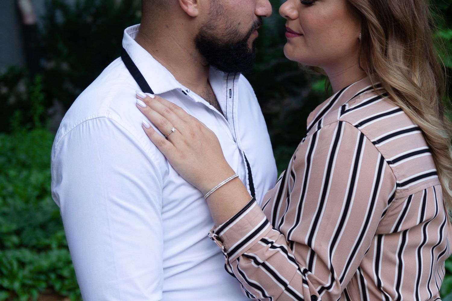 A romantic couple sharing an intimate moment outdoors in striped and white clothing.