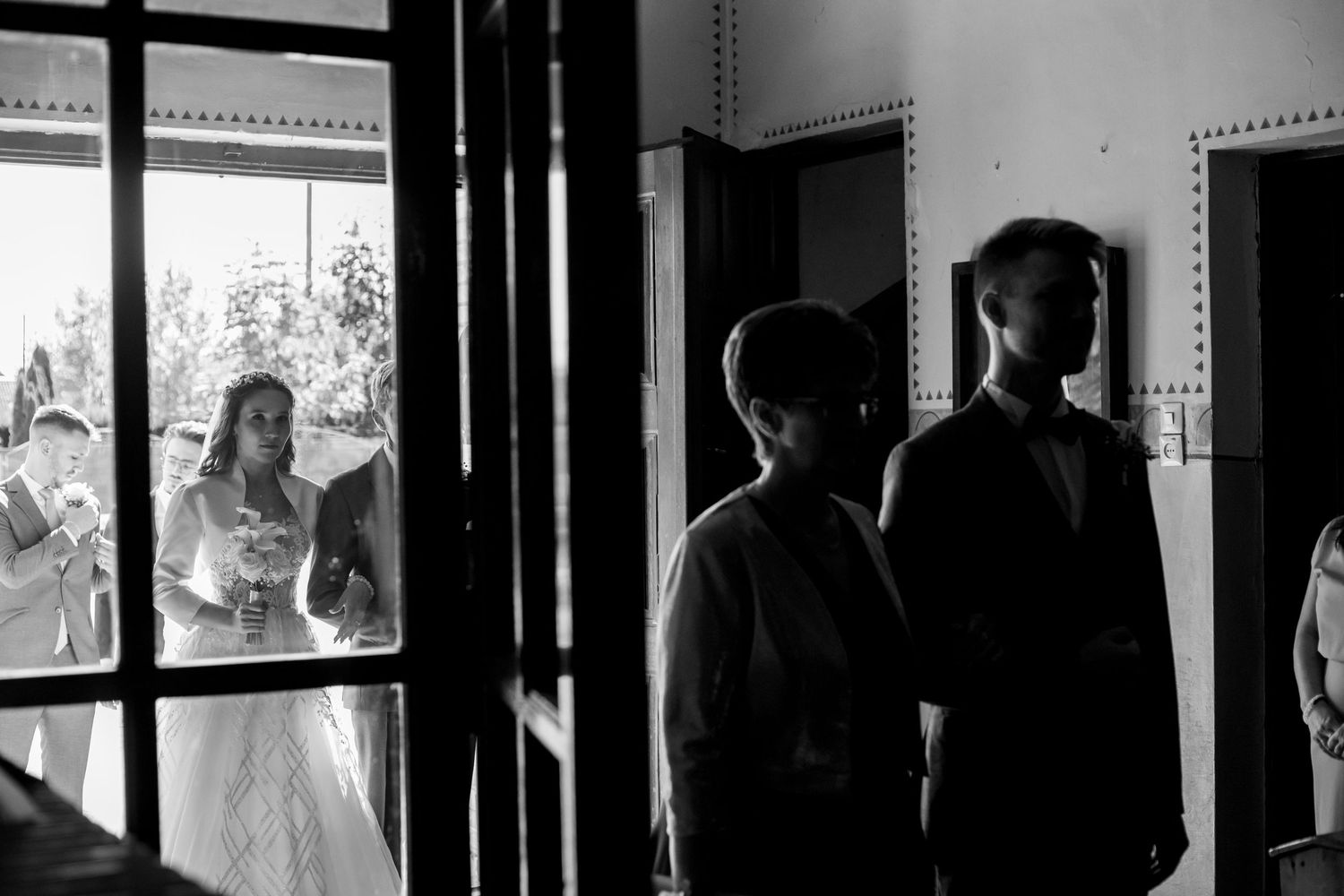Artistic black and white silhouette of wedding party through doorway.
