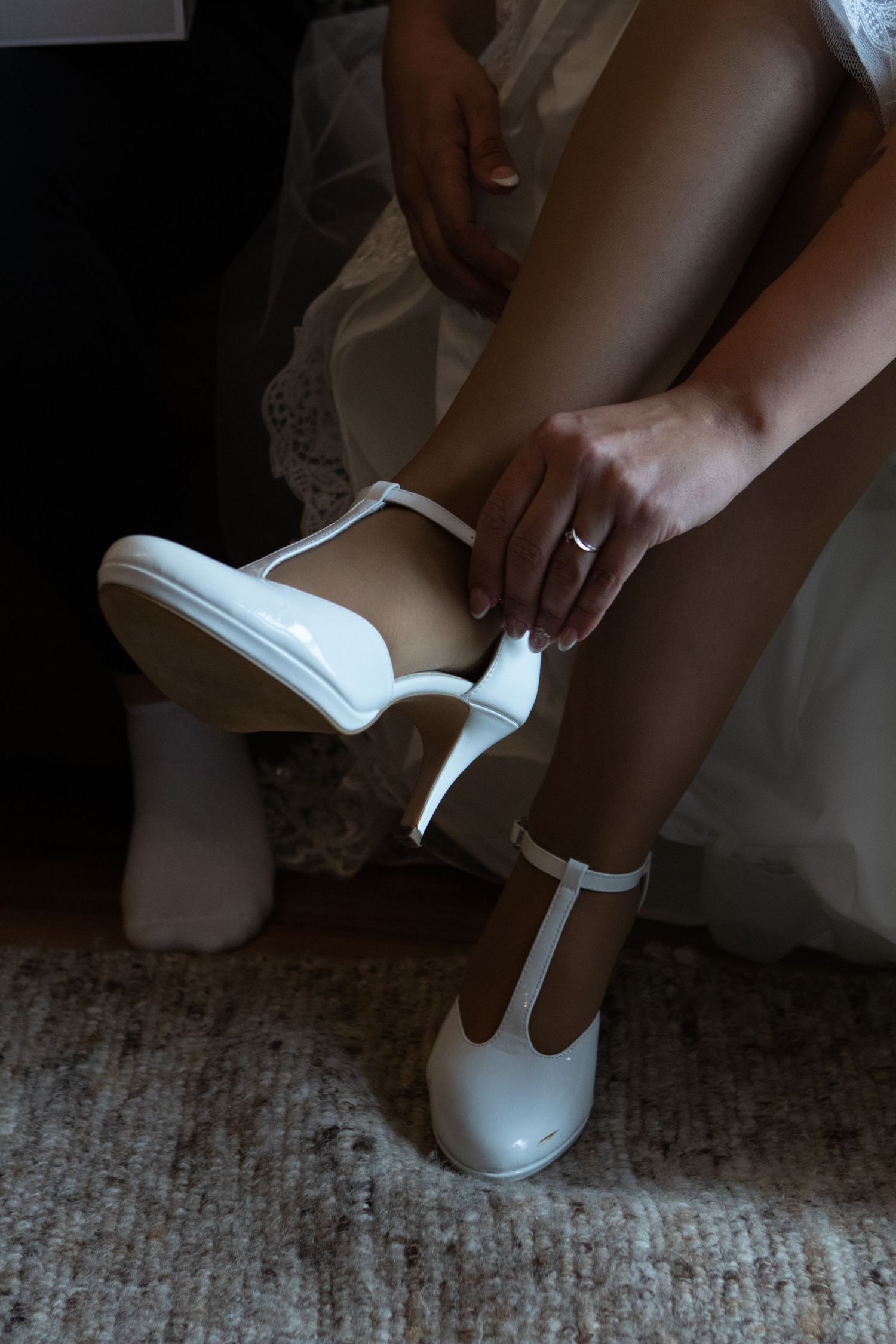 Sequence of putting on white wedding shoes with delicate lace details.