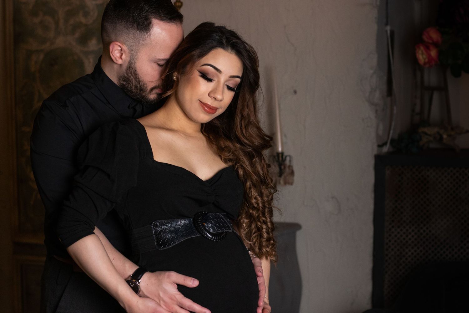 Intimate couple's photoshoot in moody indoor setting with dramatic lighting.