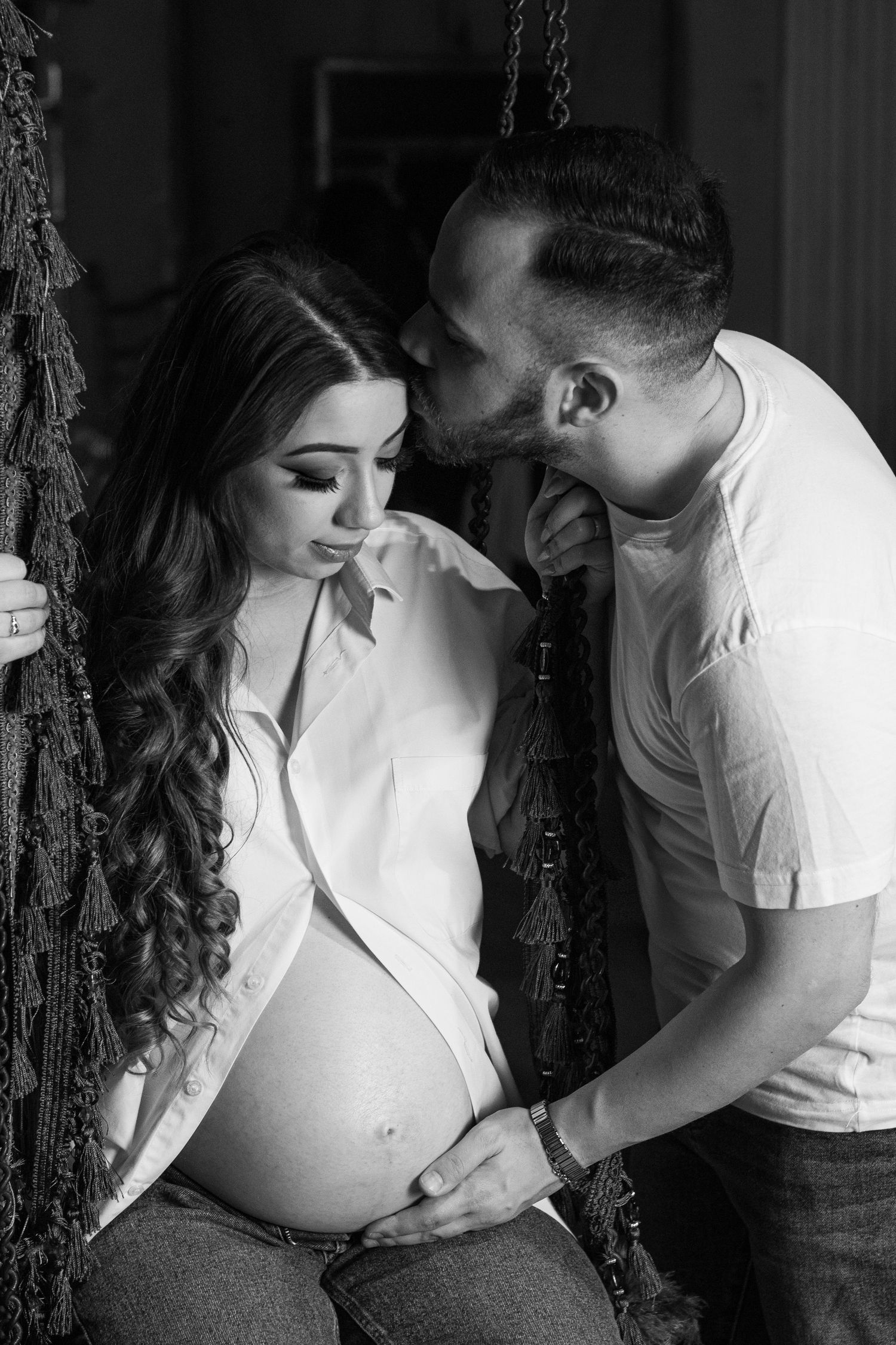 Intimate black and white maternity photo shoot with couple in white shirts.