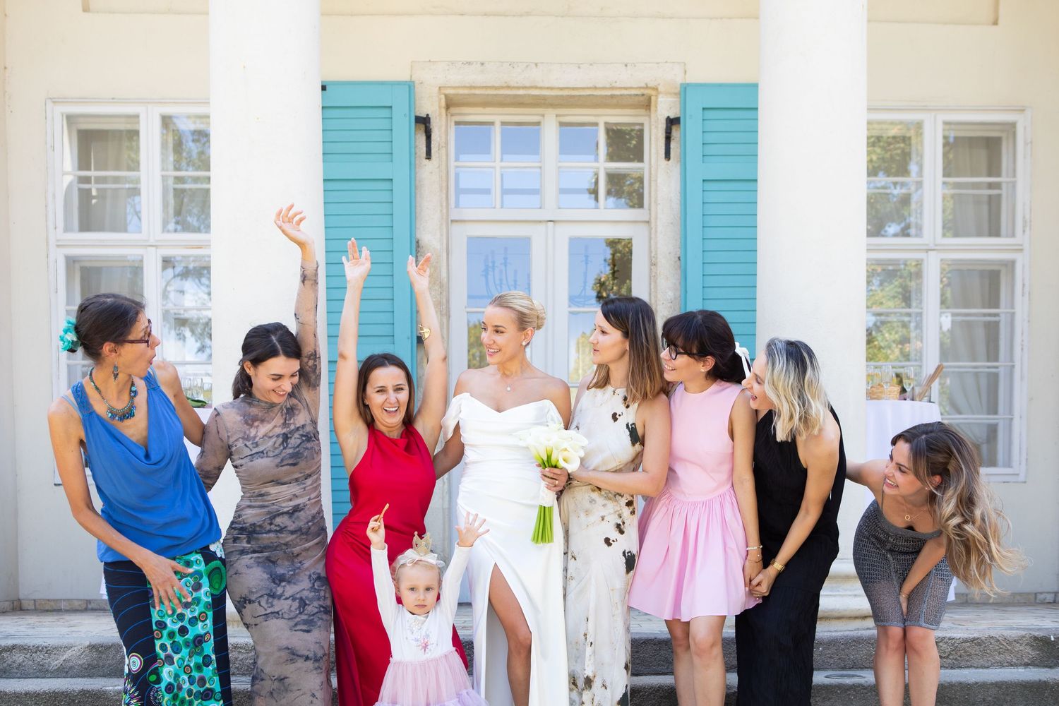 Wedding guests posing together on steps of a white building with turquoise accents.