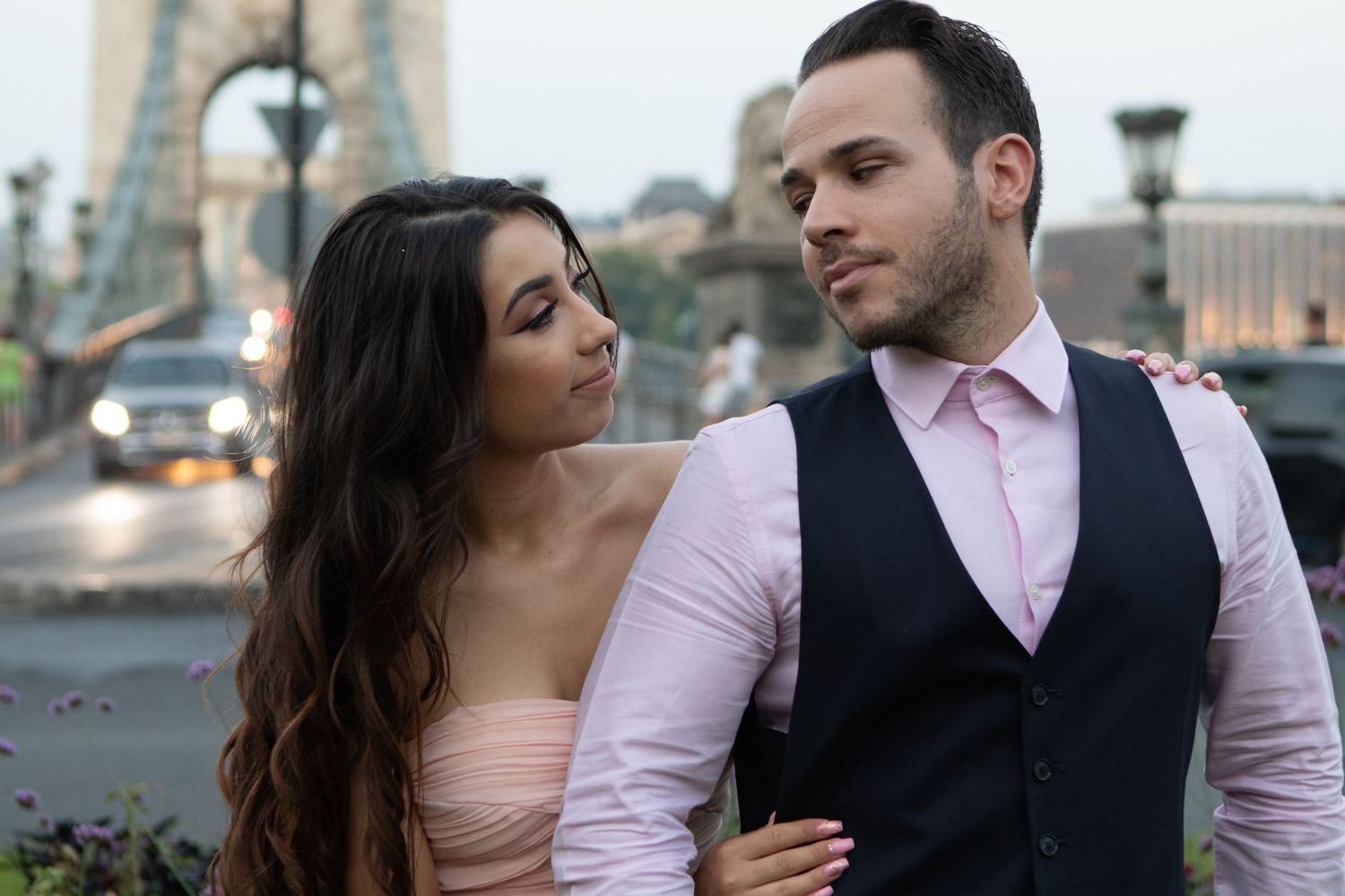 Couple in formal wear sharing intimate moments on a bridge during sunset.