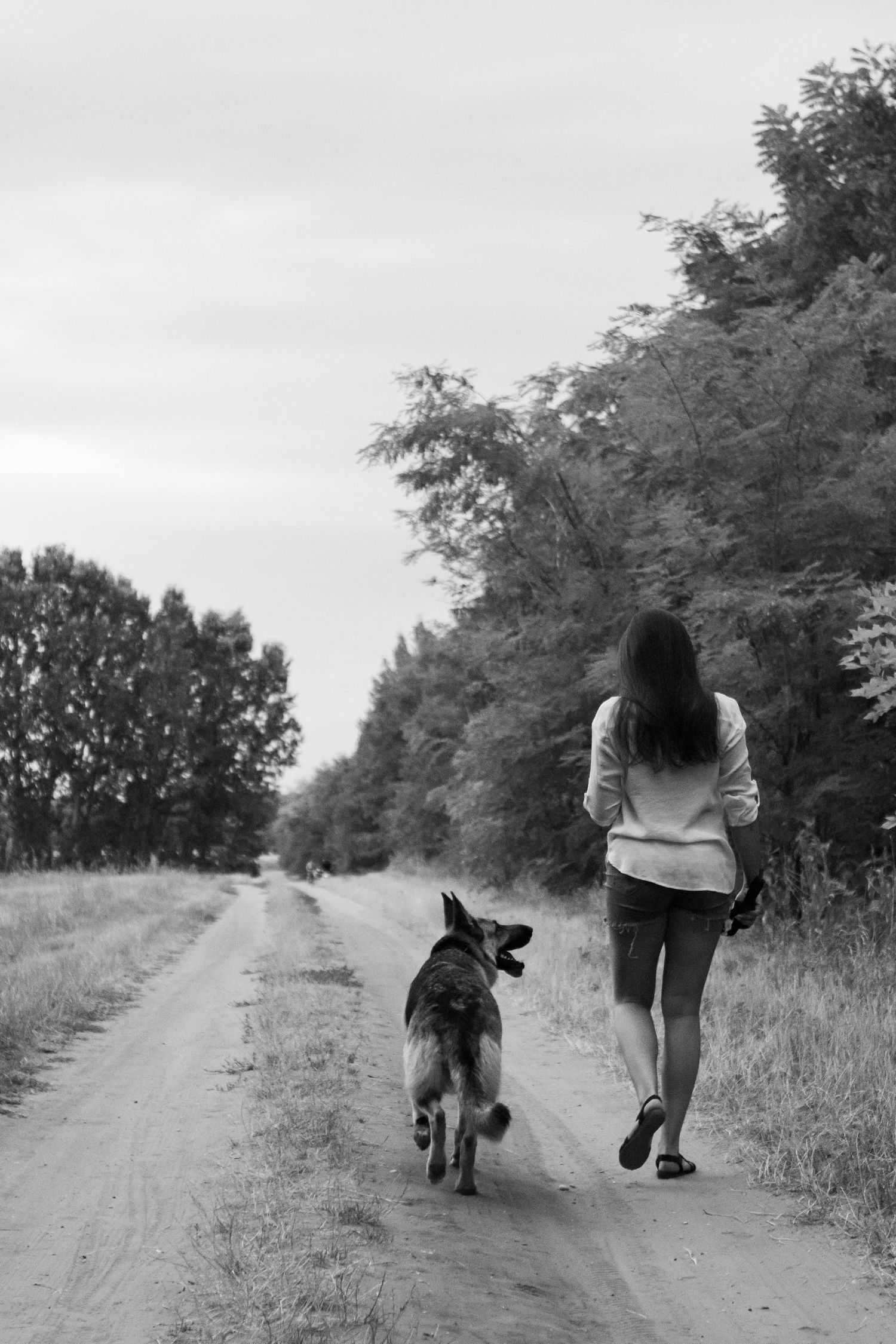 Black and white family photo of couple walking down rural path.