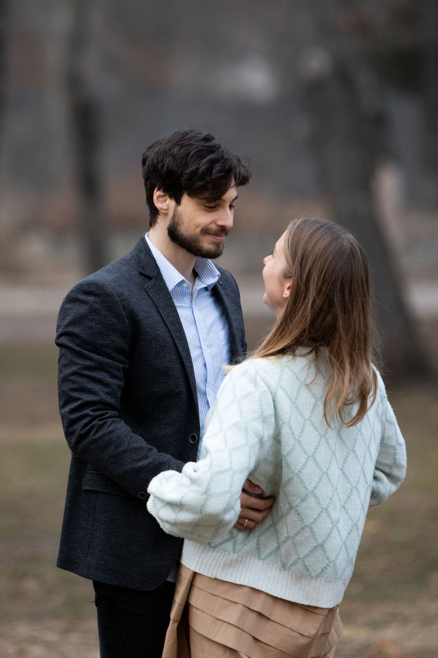 A couple in winter clothing sharing a tender moment in an outdoor setting.