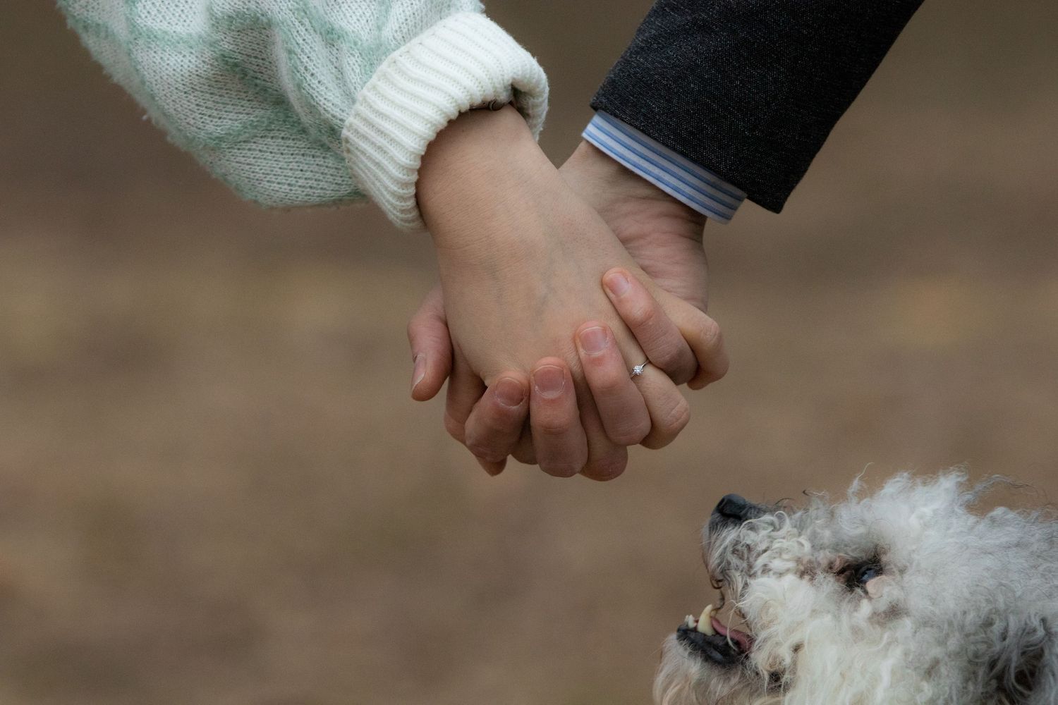 Close-up of intertwined hands wearing warm winter clothing outdoors.