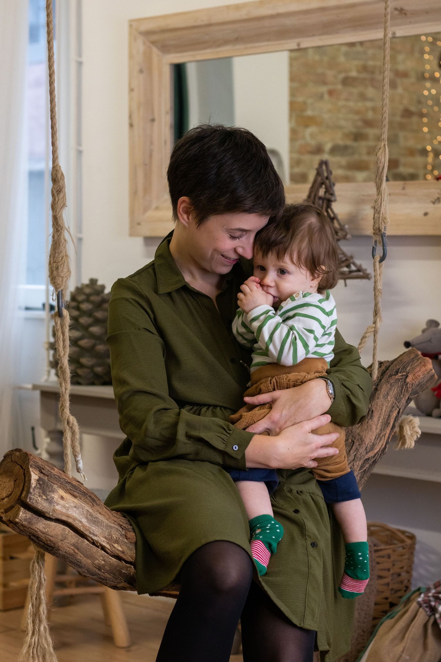 Indoor family portrait on rustic wooden swing with natural lighting.