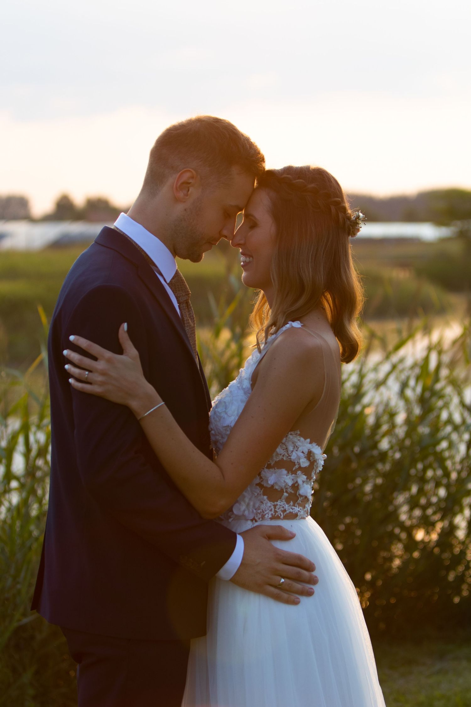 Romantic sunset silhouettes of newlyweds embracing in a field.