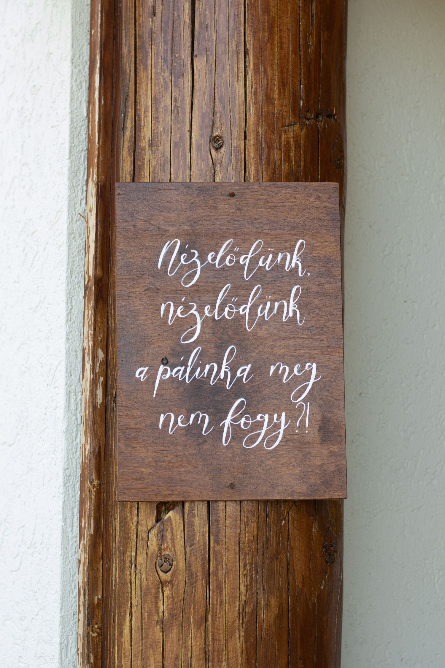 Rustic wooden signs with elegant white calligraphy text mounted on white wall.