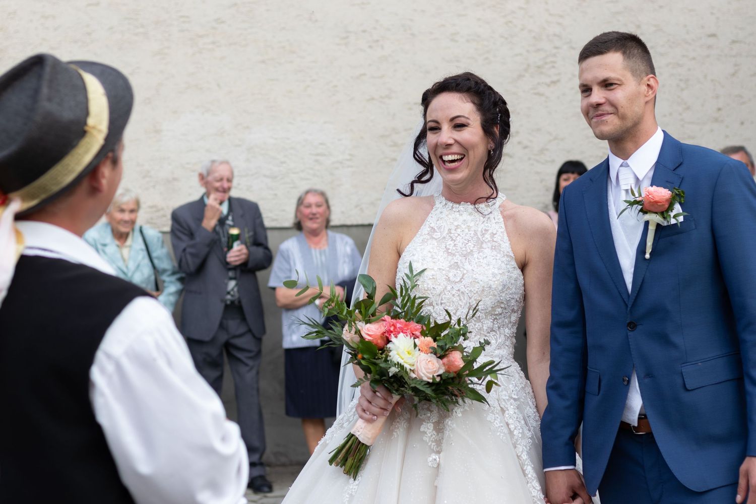 Wedding ceremony outdoors with couple and guests sharing a joyful moment with white dress and navy suit.