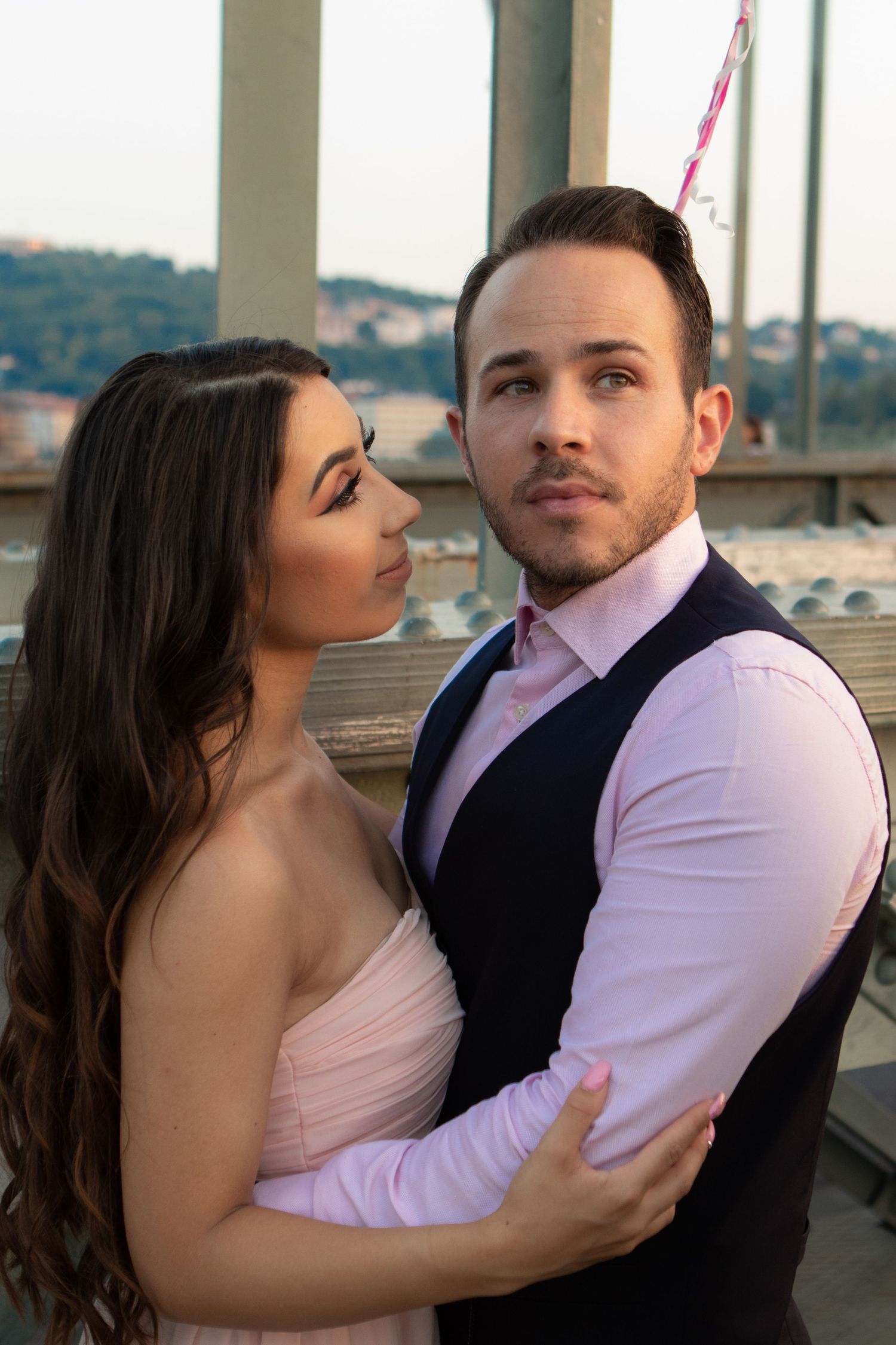 Romantic couple in formal attire sharing intimate moments against a scenic backdrop.