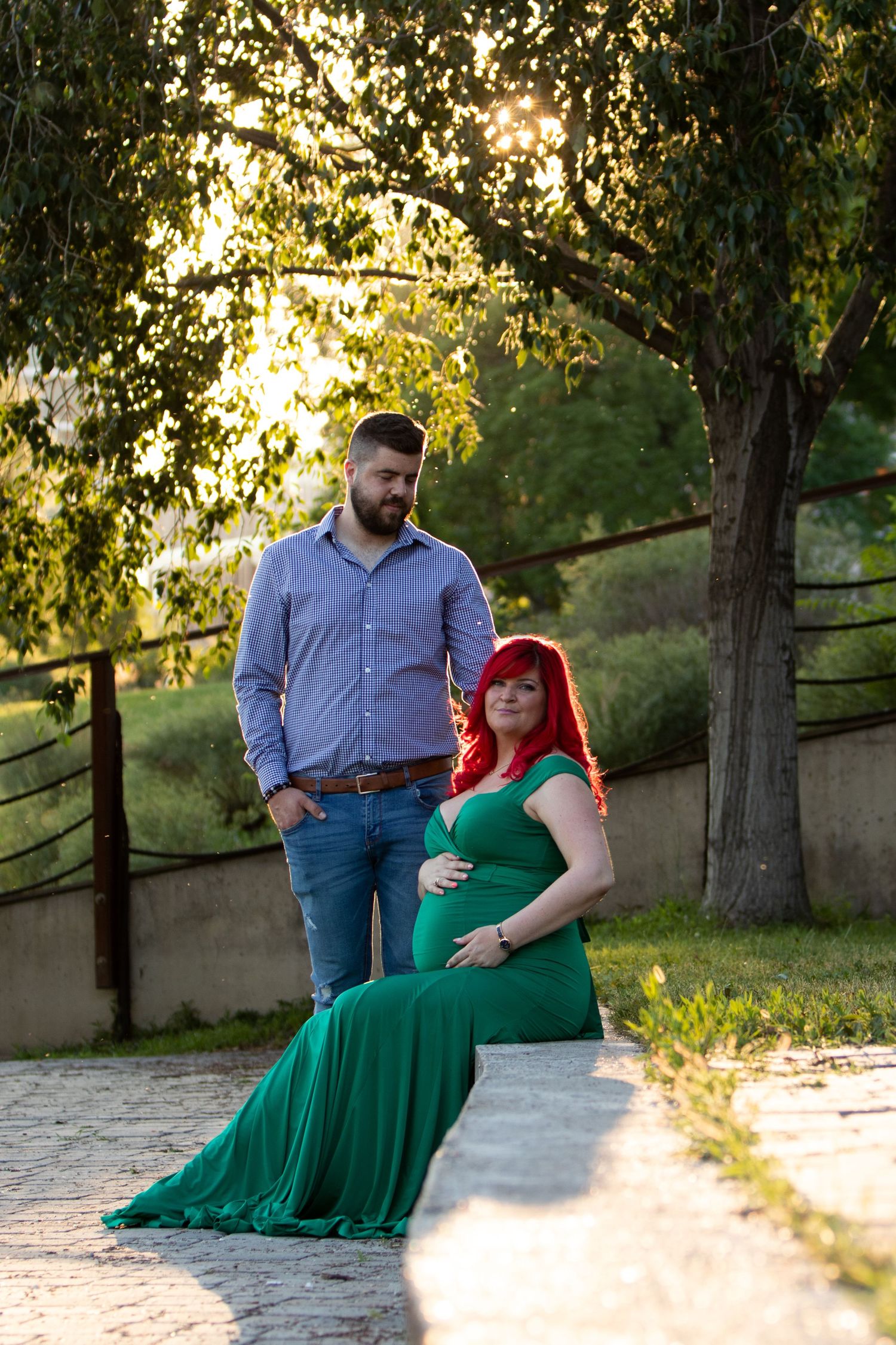Couple poses together outdoors during golden hour sunset in a park setting.