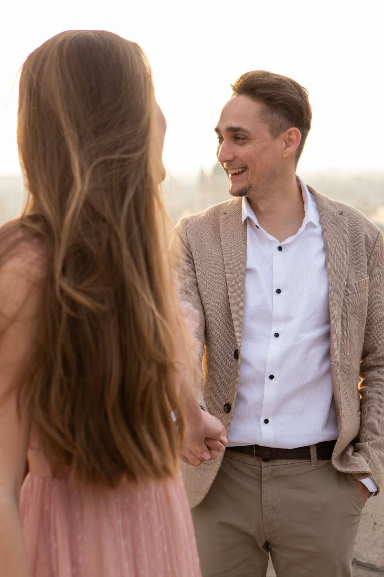 A couple in formal attire shares romantic moments during a sunset photoshoot.