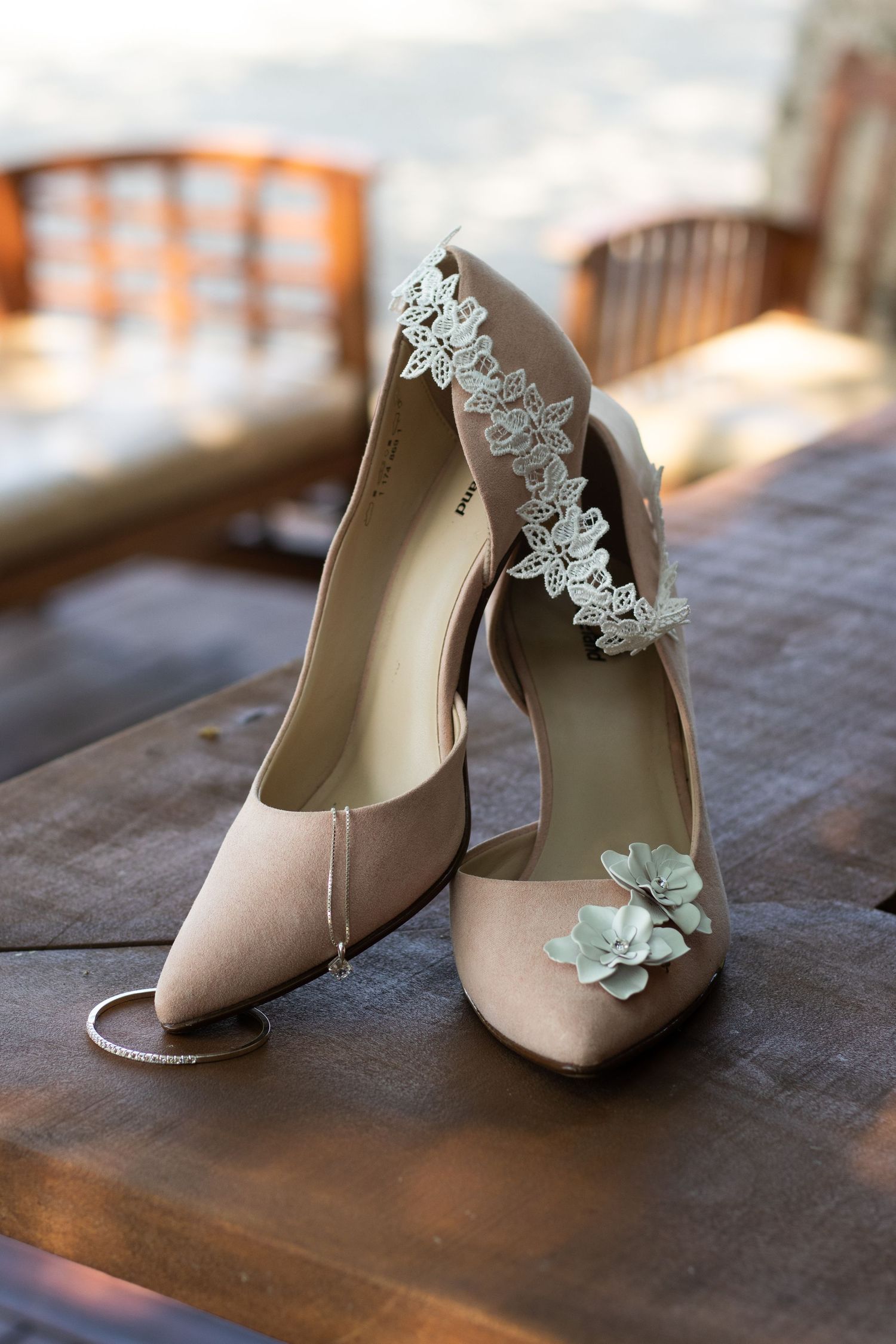 Elegant beige bridal shoes with lace details and mint accents on wooden surface.
