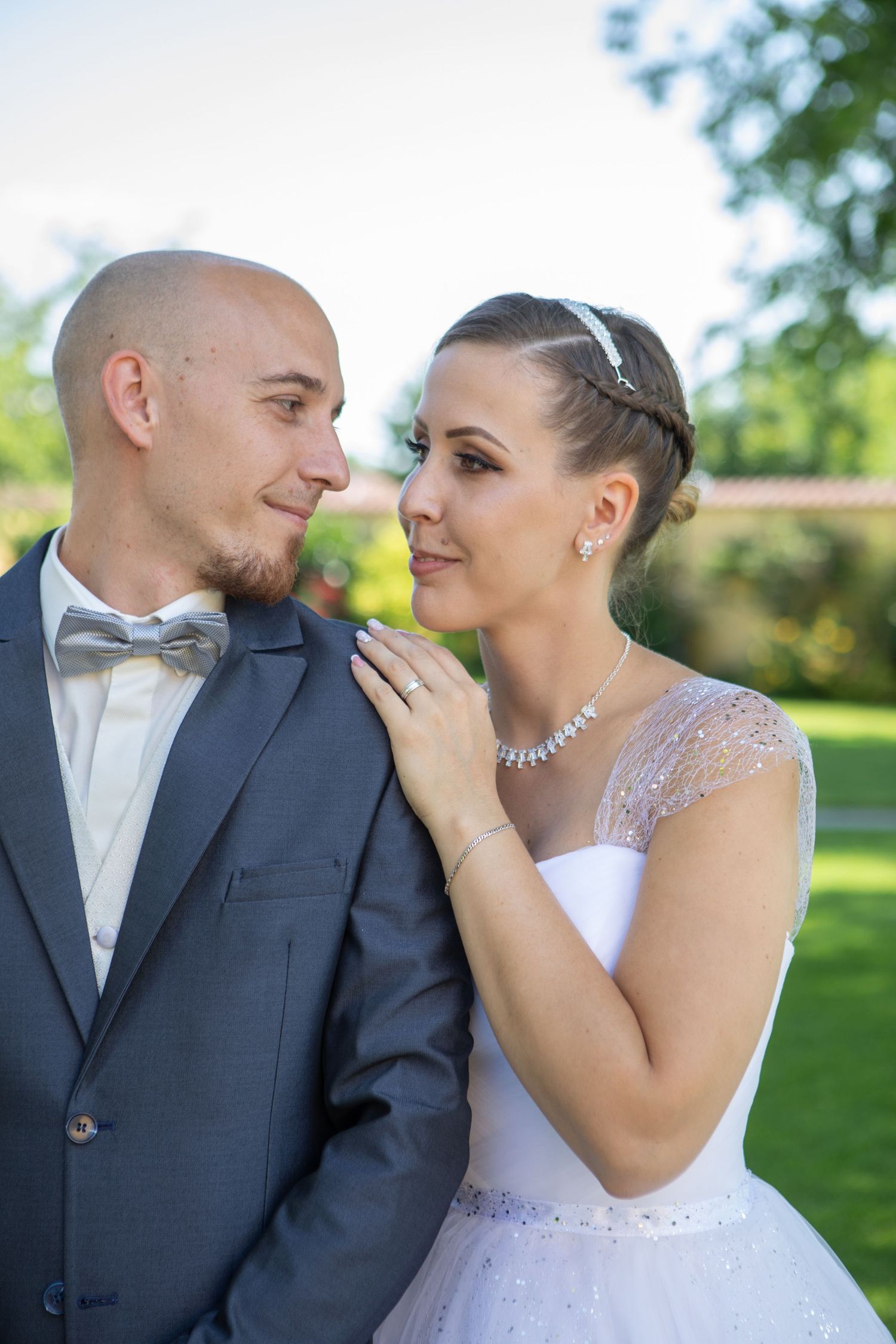 Romantic wedding portrait captured in a sunny garden setting.
