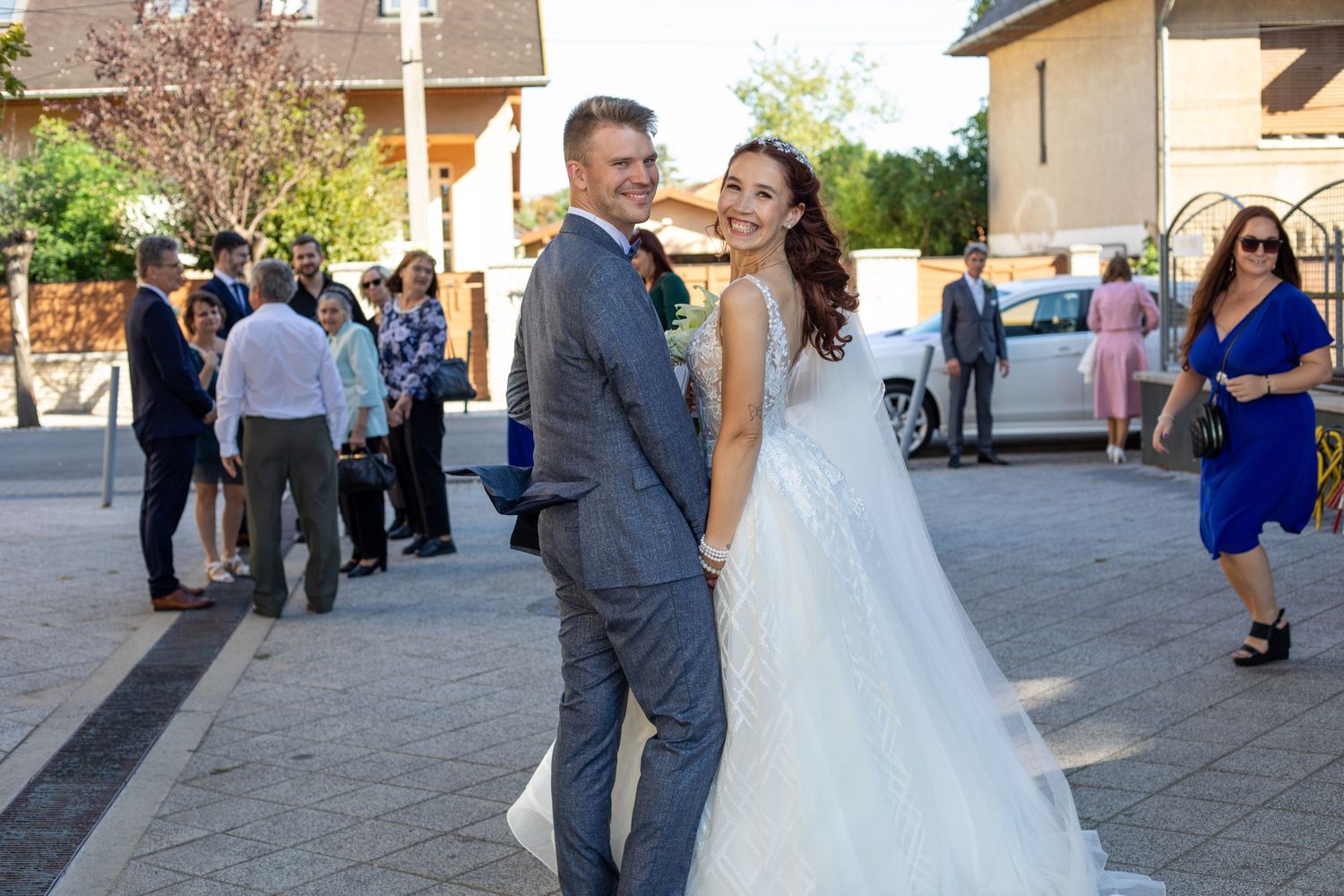 Wedding celebration outside a venue with guests mingling in formal attire.