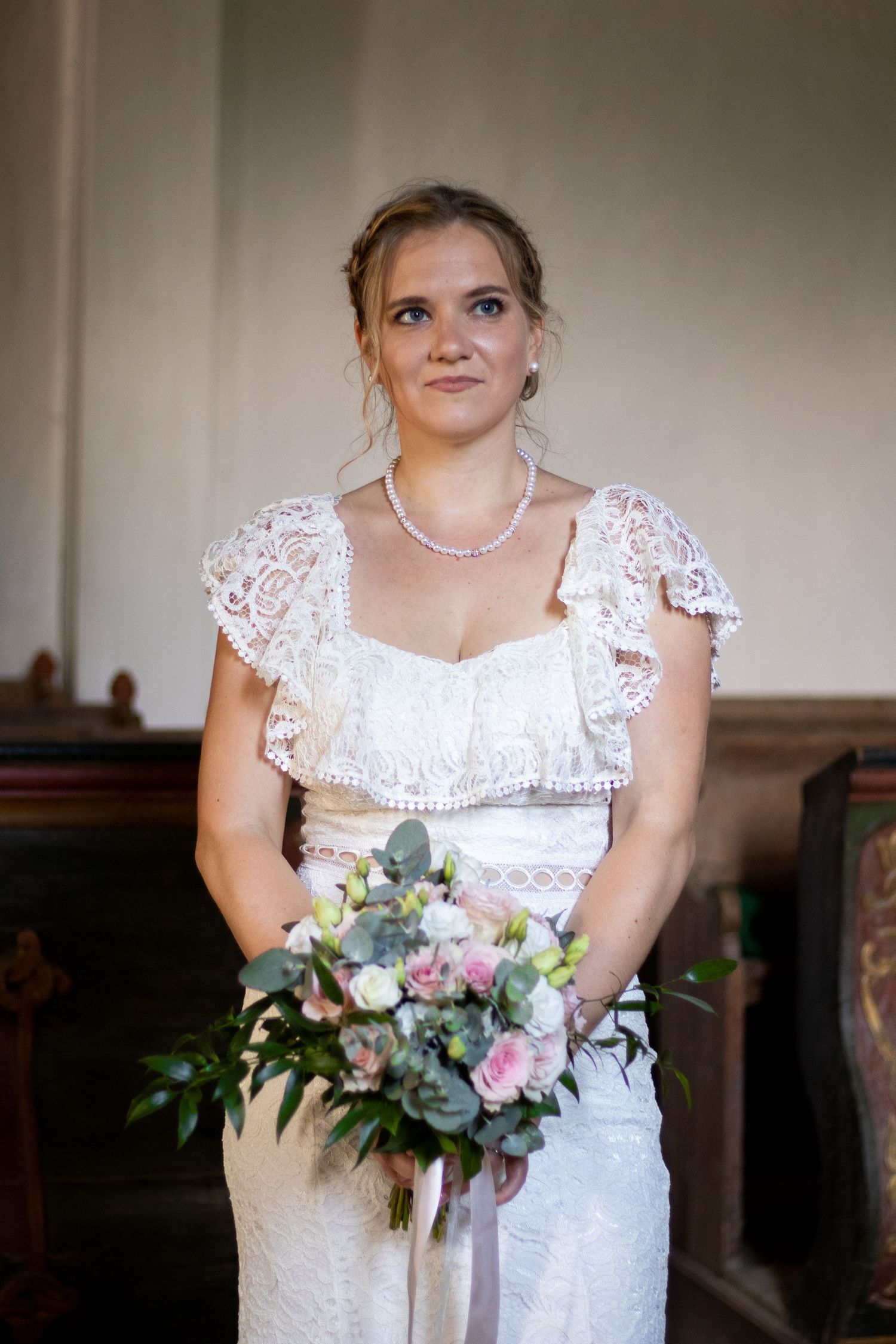 Elegant bridal portrait showcasing lace dress details and fresh floral bouquet.