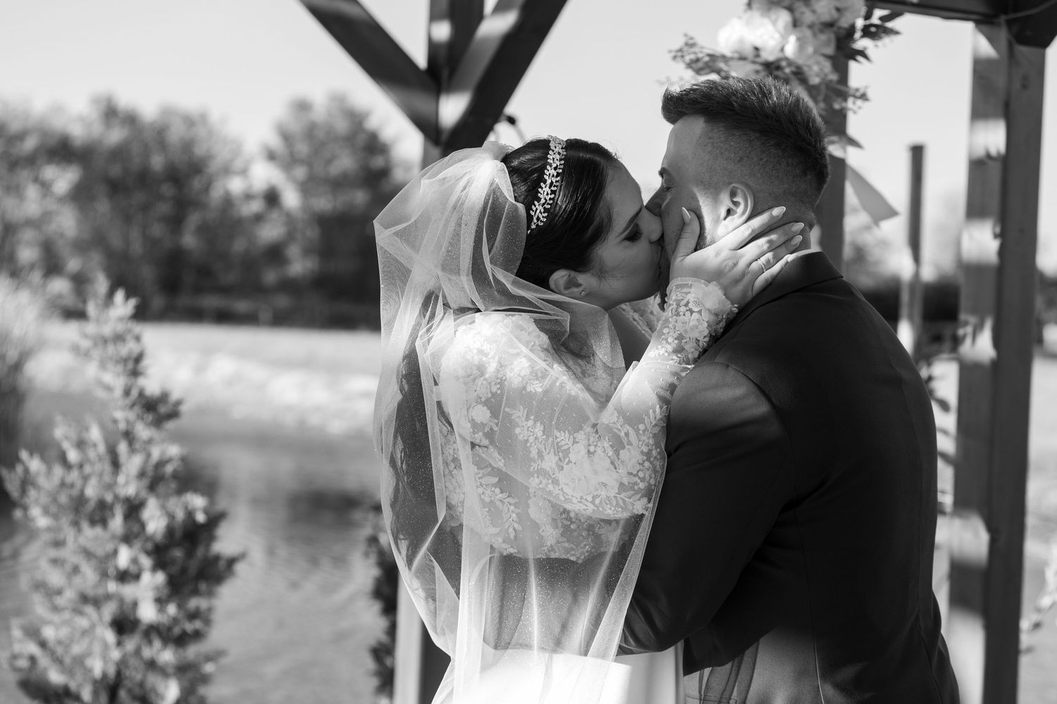 Black and white romantic outdoor wedding portrait under wooden structure.