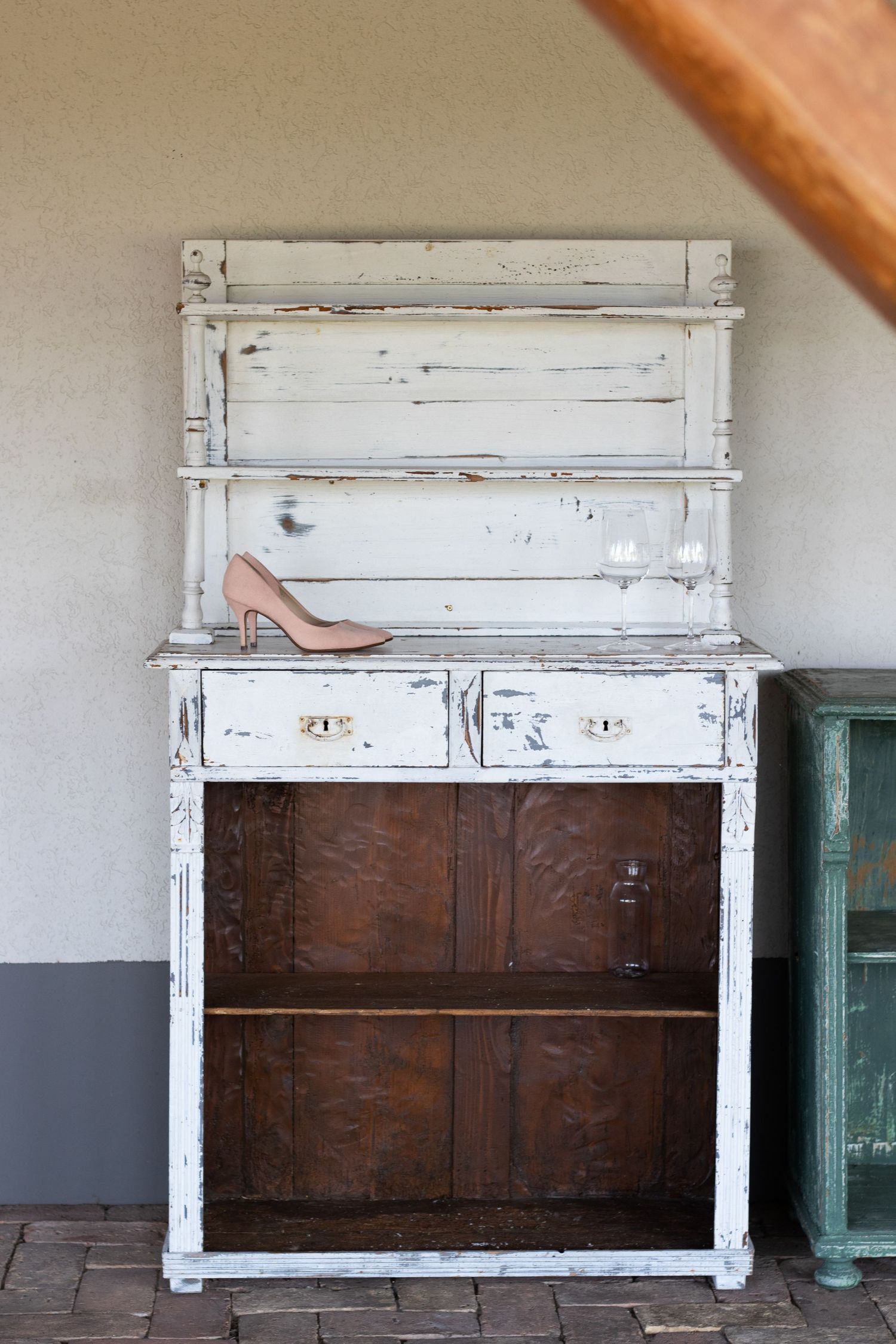 Vintage distressed white cabinet with dark wood panels against neutral wall.