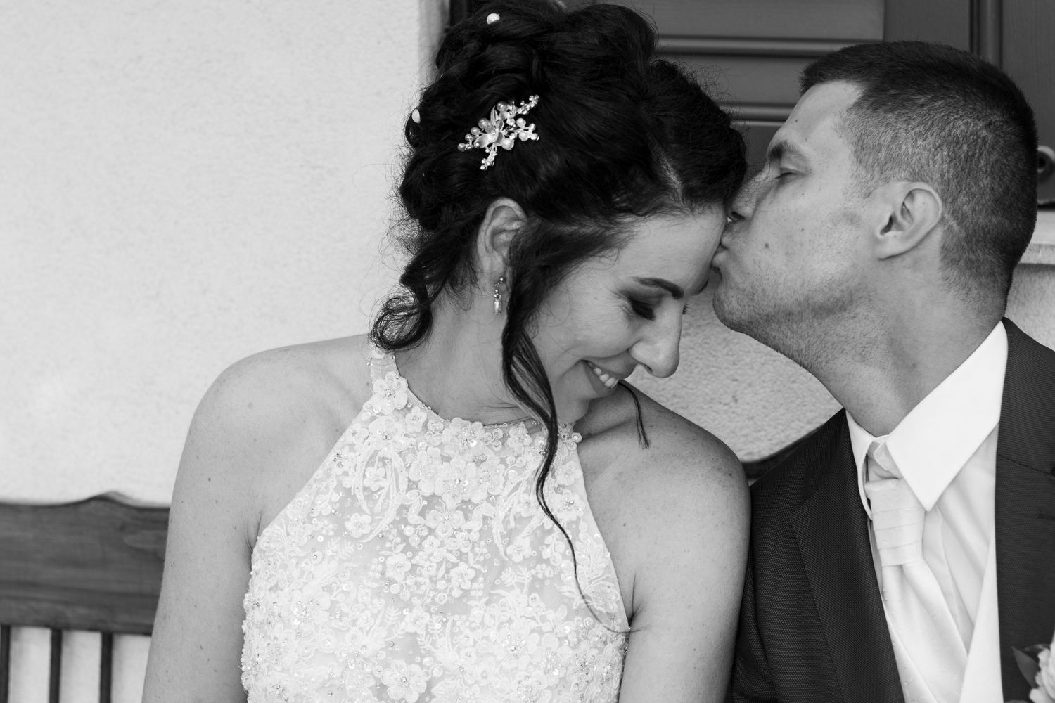An intimate black and white wedding moment captured against a white wall.