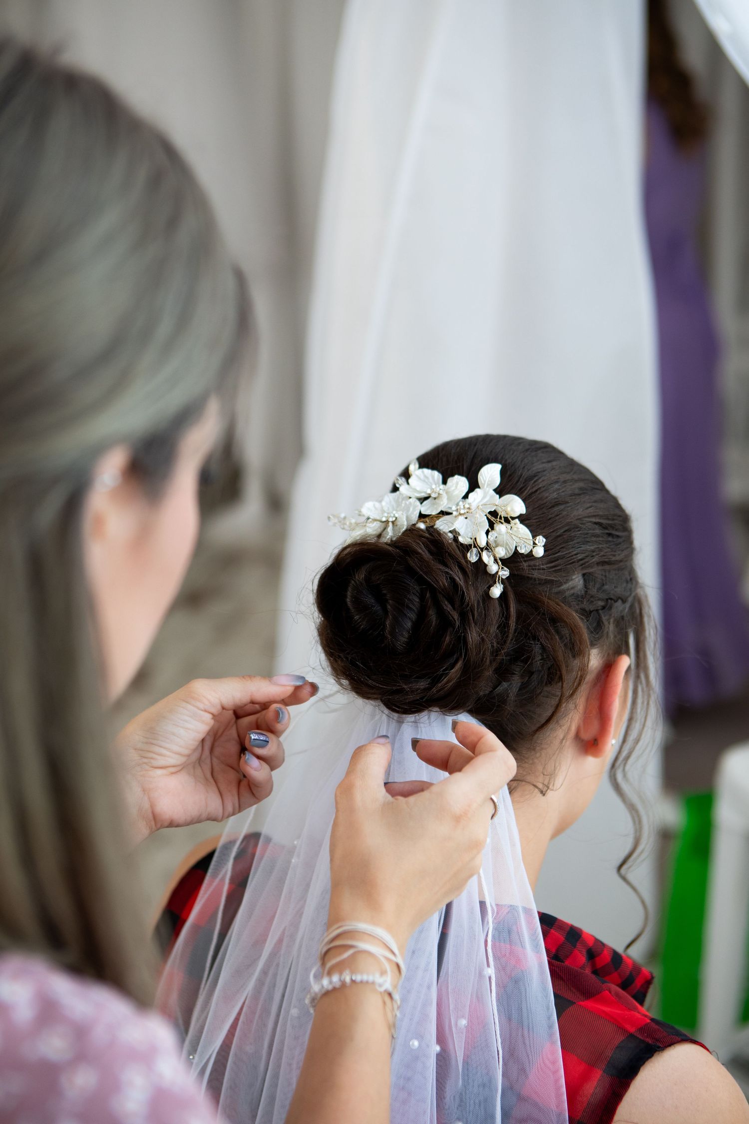 Final touches being added to a bridal hairstyle with delicate white floral hair accessories and veil.