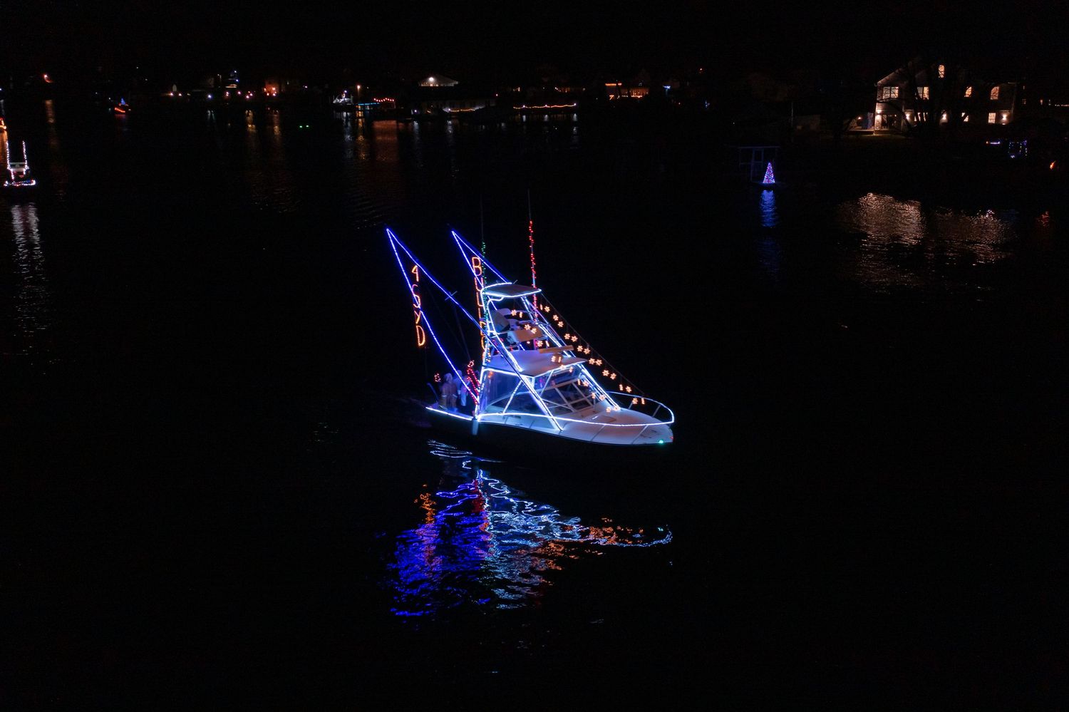 Drone photo of a decorated boat at night surrounded by darkness and reflections.