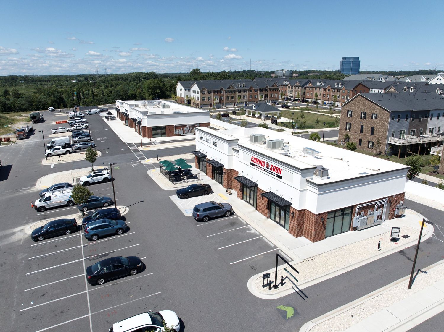 Aerial view of a retail shopping center with parking lot and surrounding businesses.