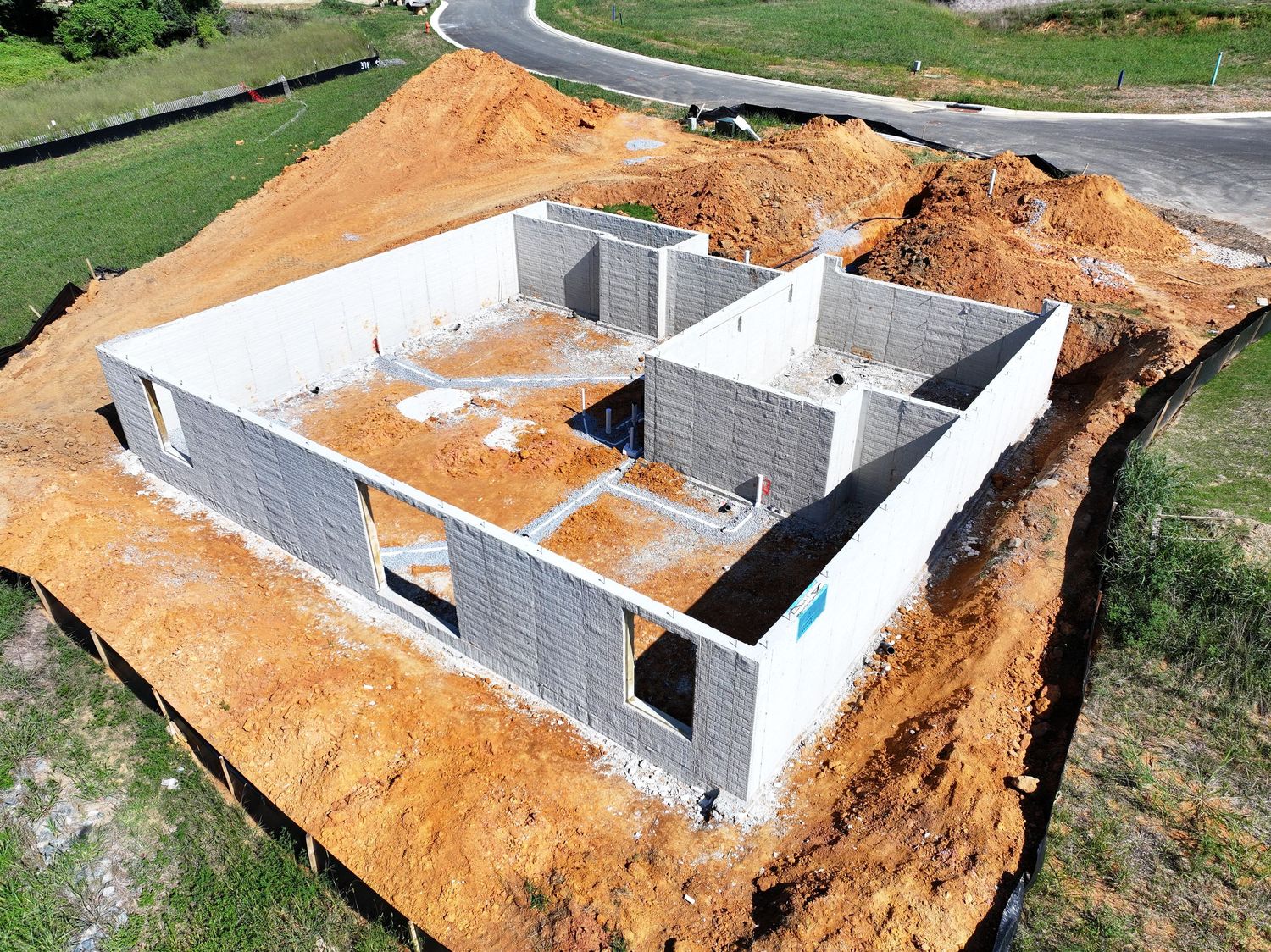 Aerial view of an active construction site with earthwork, foundations, and temporary access roads.