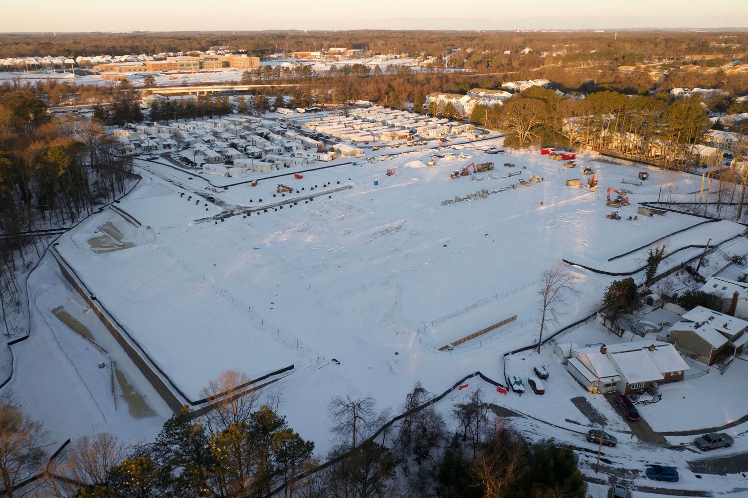 Aerial view of an active construction site with earthwork, foundations, and temporary access roads.