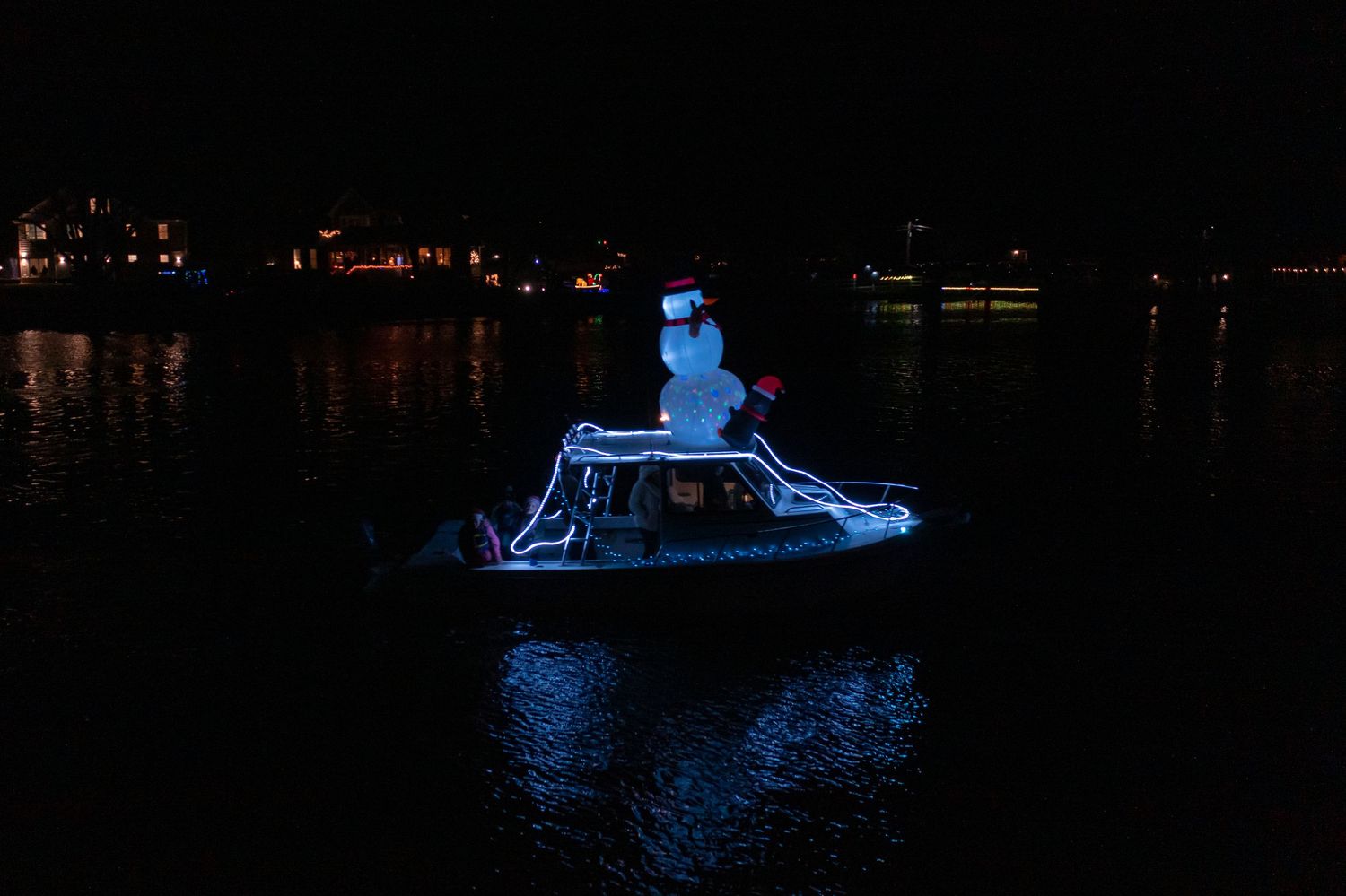 Drone photo of a decorated boat at night surrounded by darkness and reflections.
