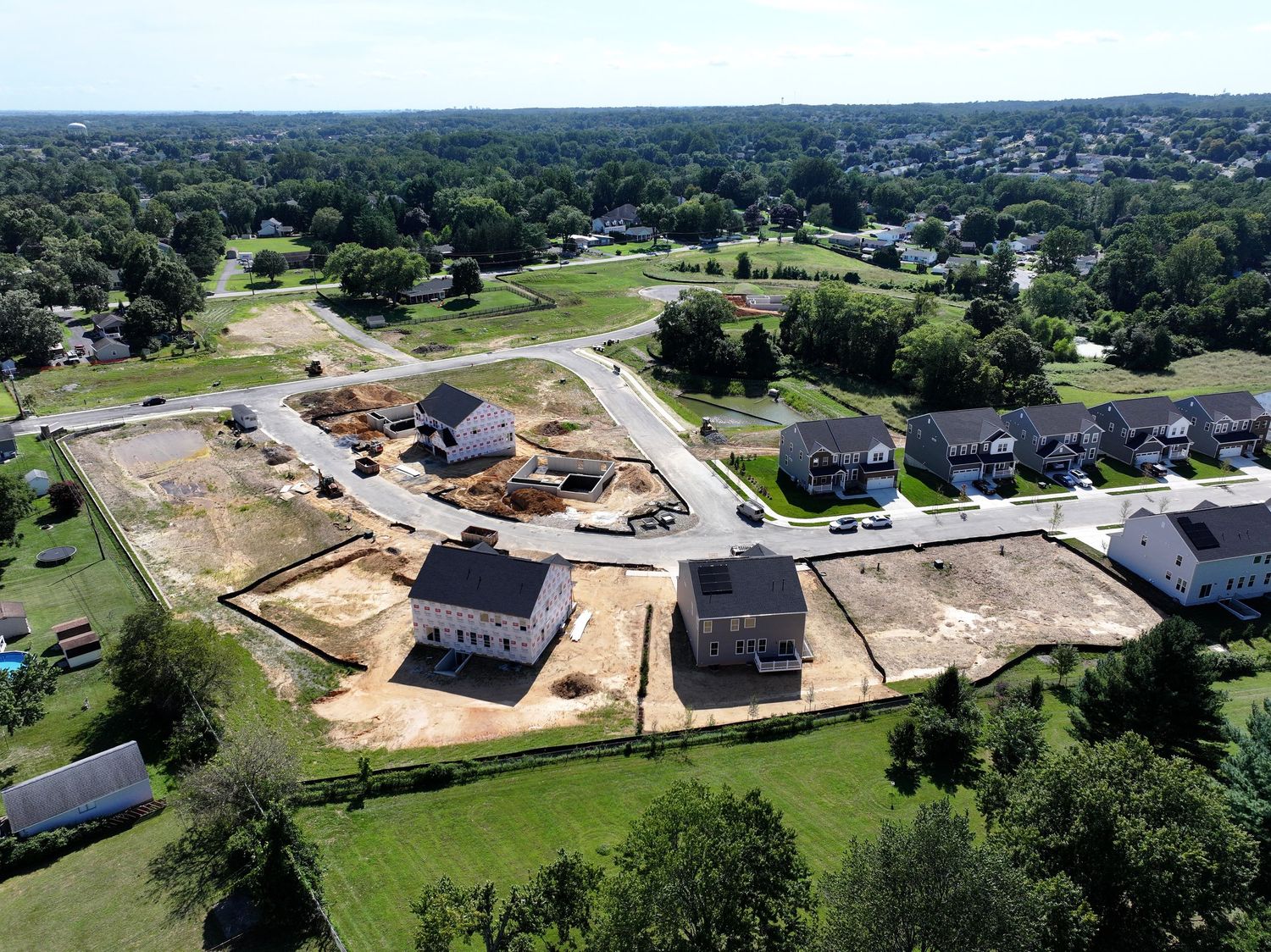 Aerial view of a large institutional building under construction surrounded by trees.