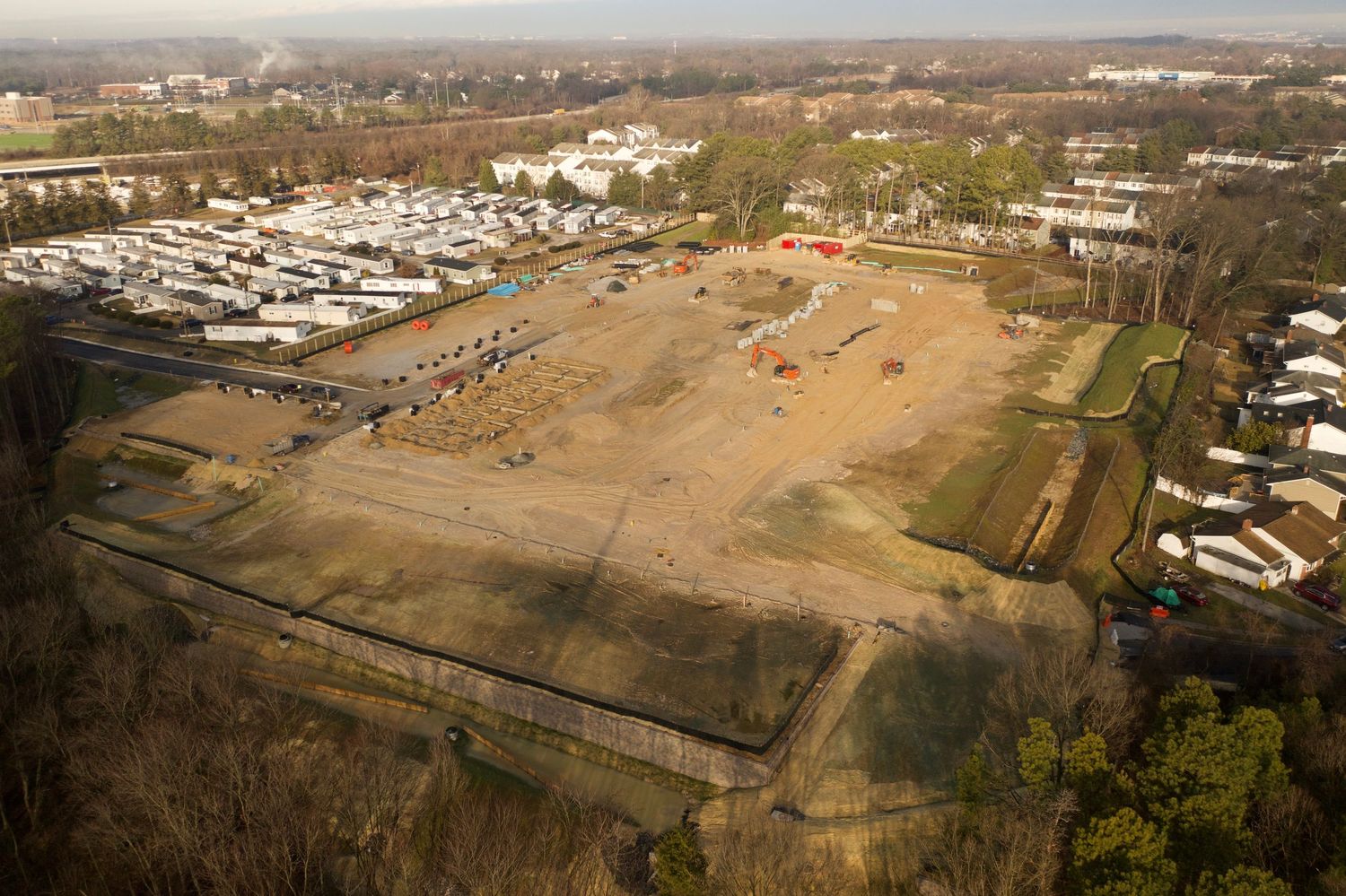 Aerial view of an active construction site with earthwork, foundations, and temporary access roads.
