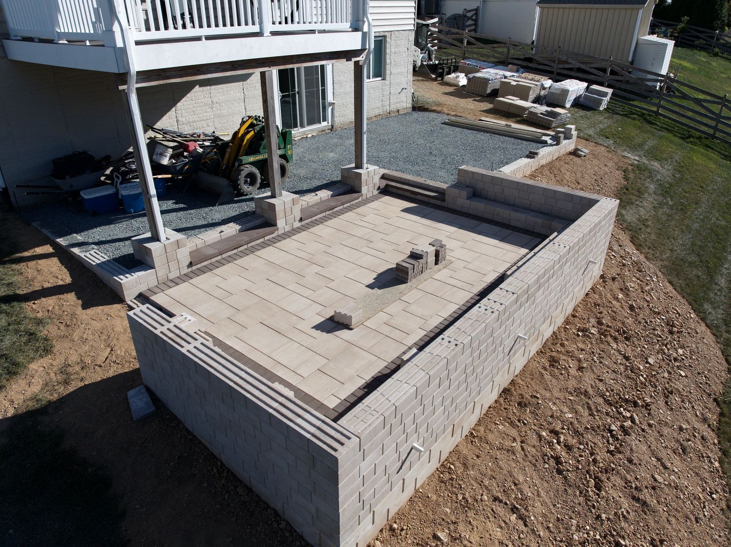 Aerial view of a backyard patio under construction with visible materials and equipment.