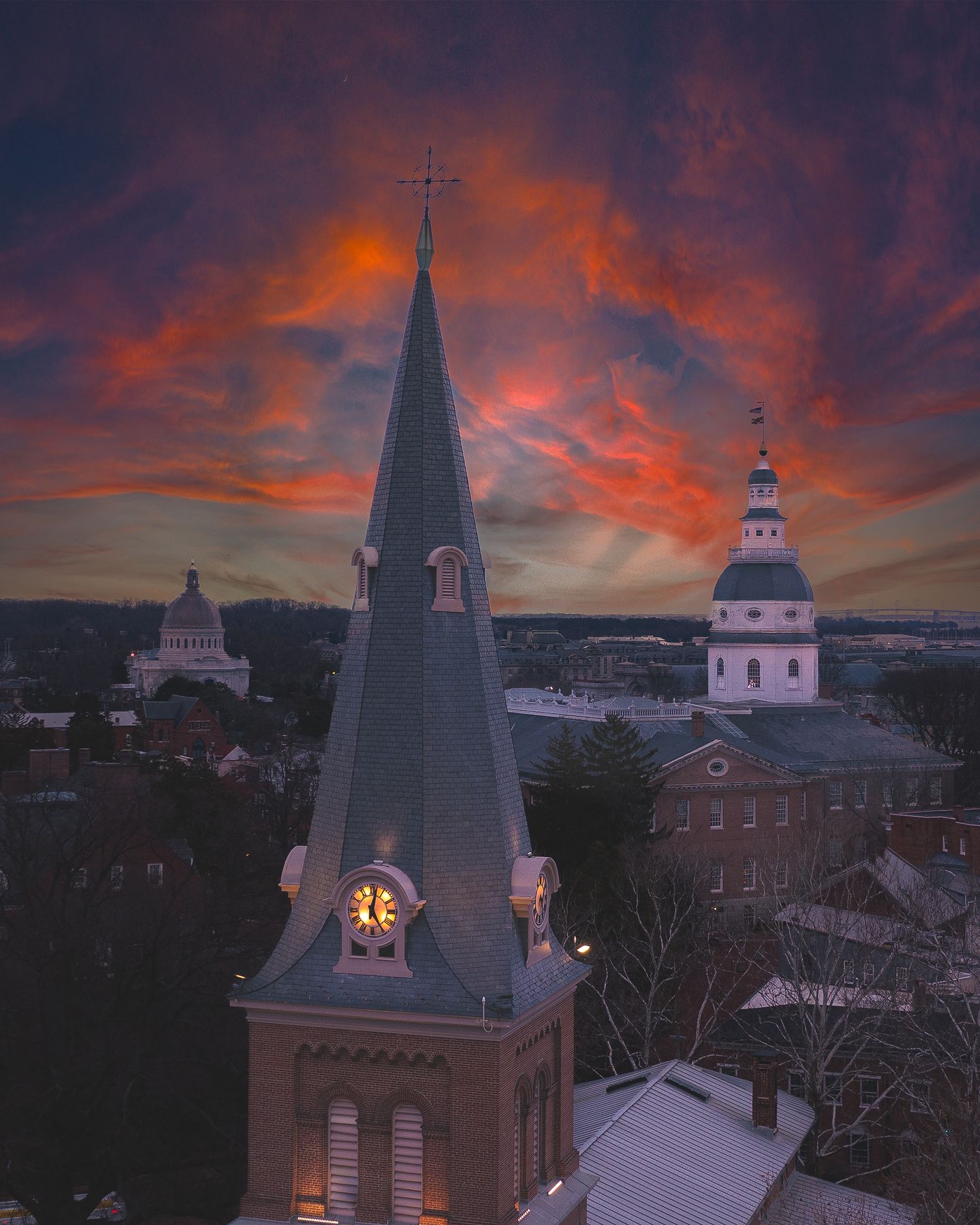 Aerial view of a historic church steeple in Annapolis at sunset with dramatic clouds.