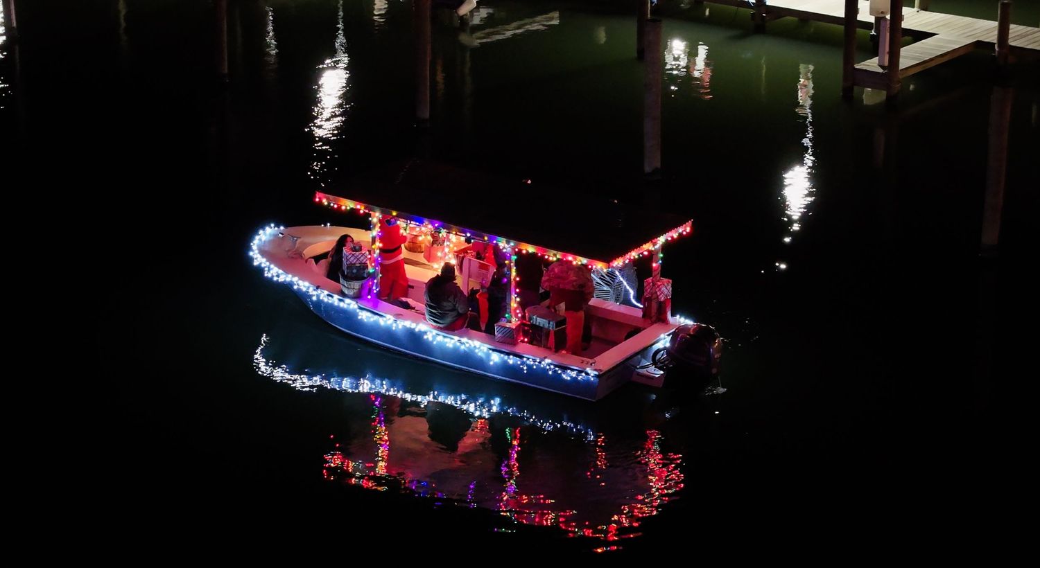 Drone photo of a decorated boat at night surrounded by darkness and reflections.