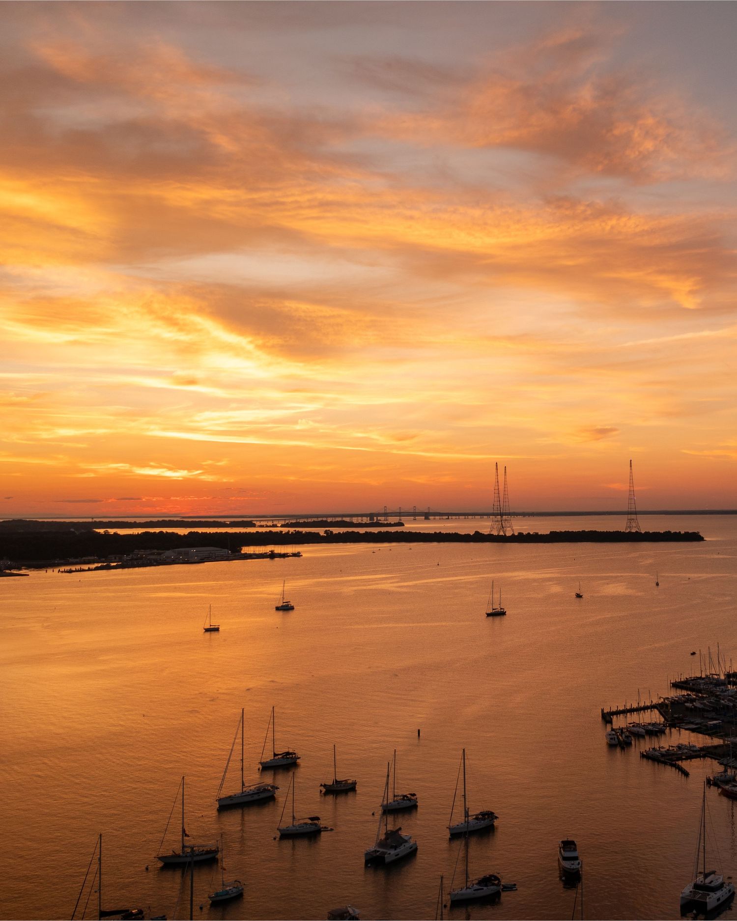 HDR aerial photo of a waterfront at sunset with calm water and scattered boats.