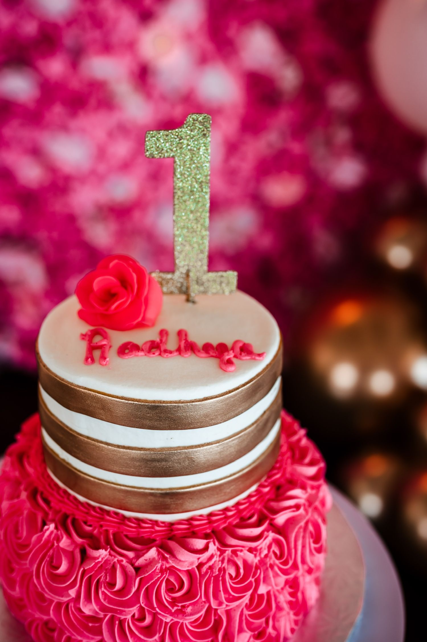 Pink rosette birthday cake topped with gold number one and silver accents.
