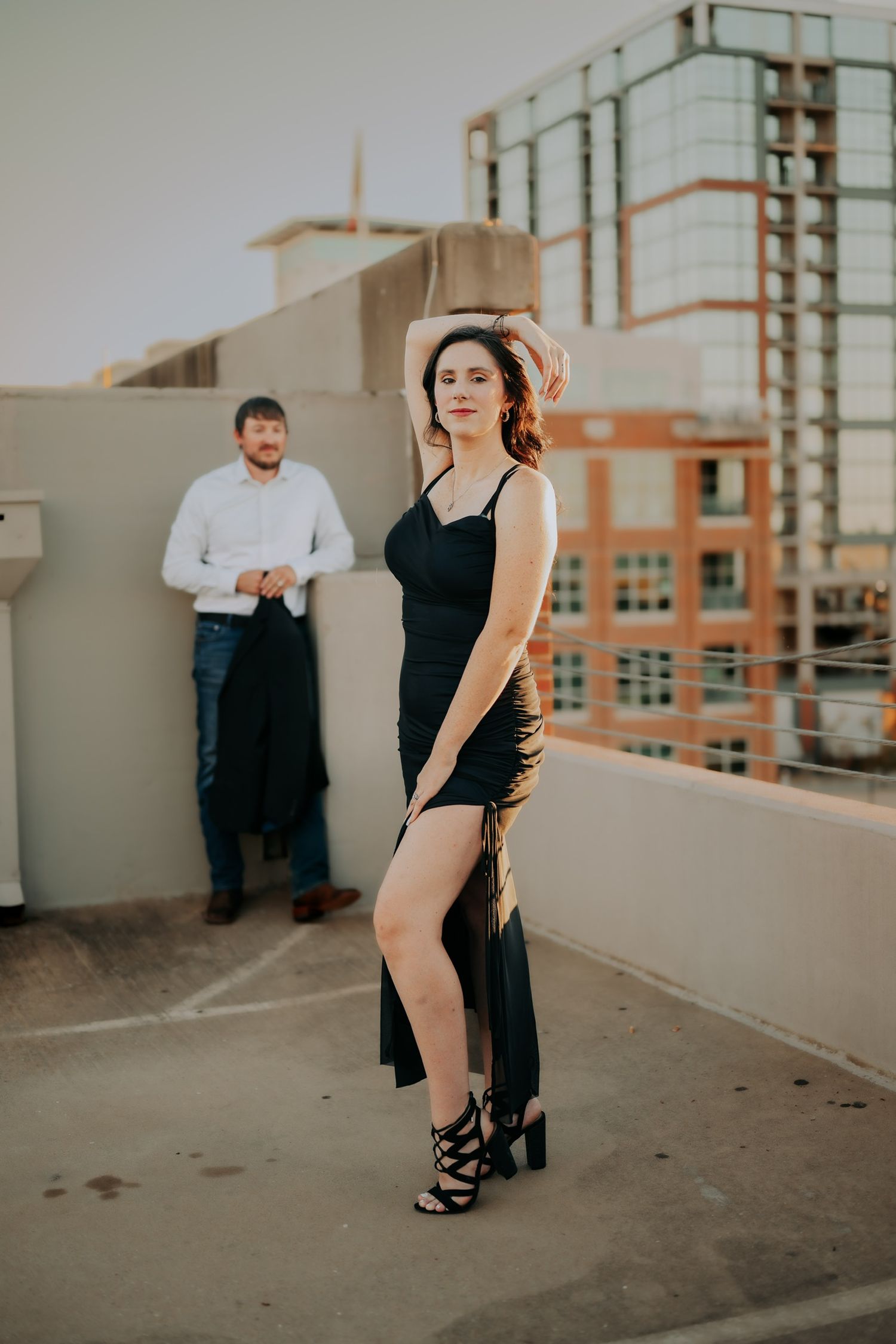 Couple in formal attire posing on urban rooftop during photoshoot.