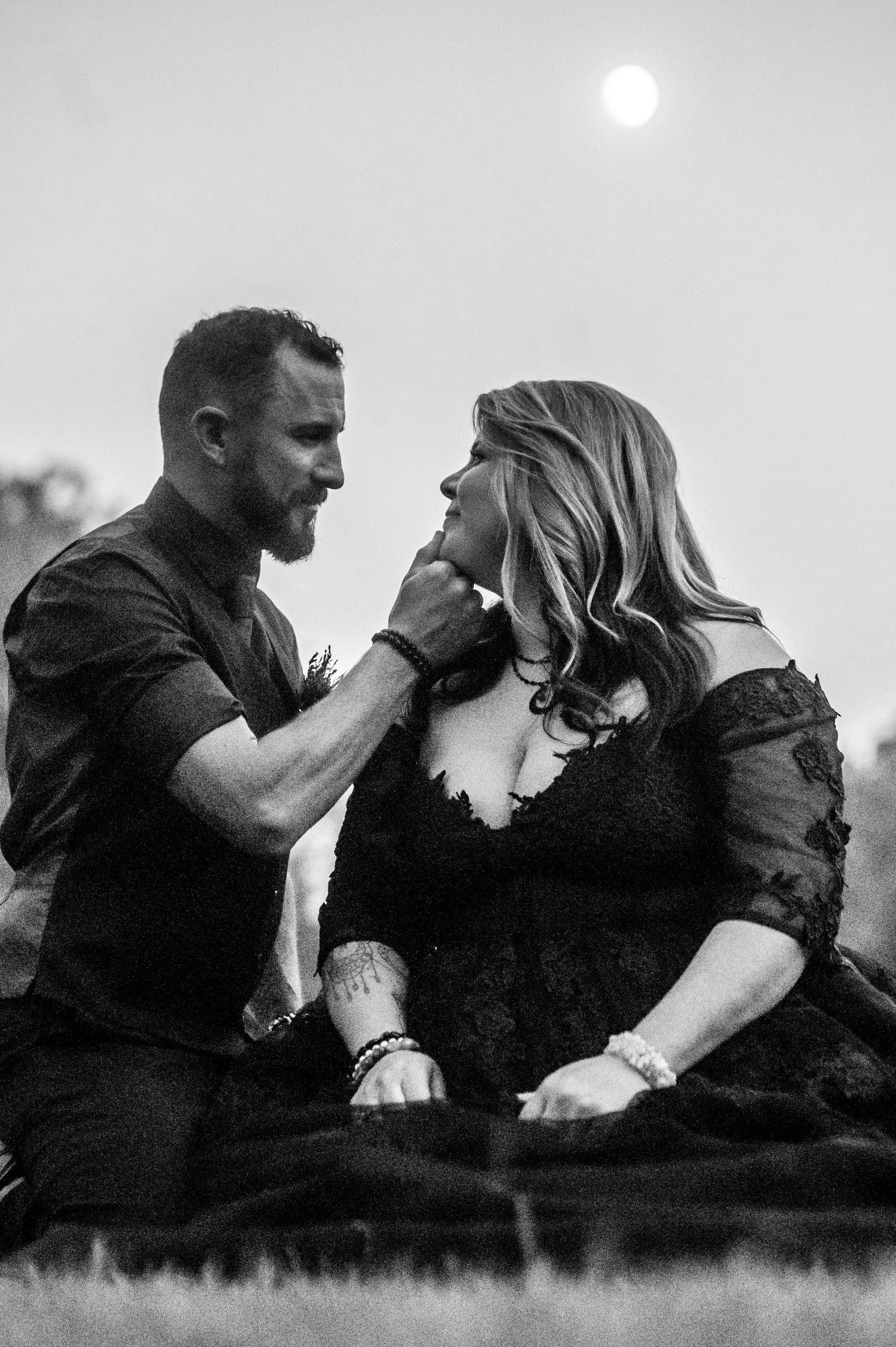 A black and white photo sequence showing a romantic couple in dark clothing sharing intimate moments outdoors.