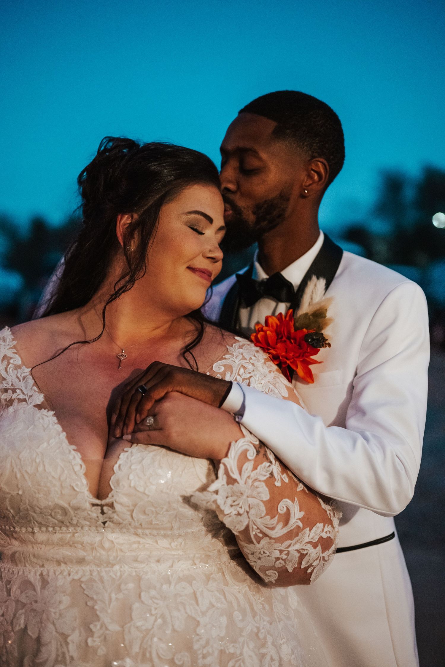 Romantic sunset wedding photo series showing newlyweds embracing in white attire against a blue sky background.