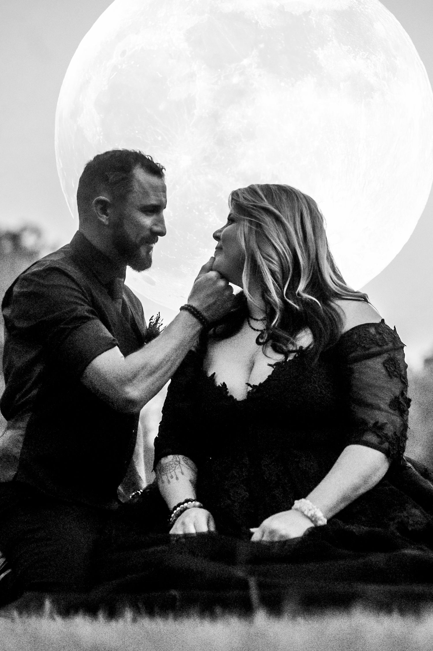 Silhouetted couple embracing against dramatic full moon background.