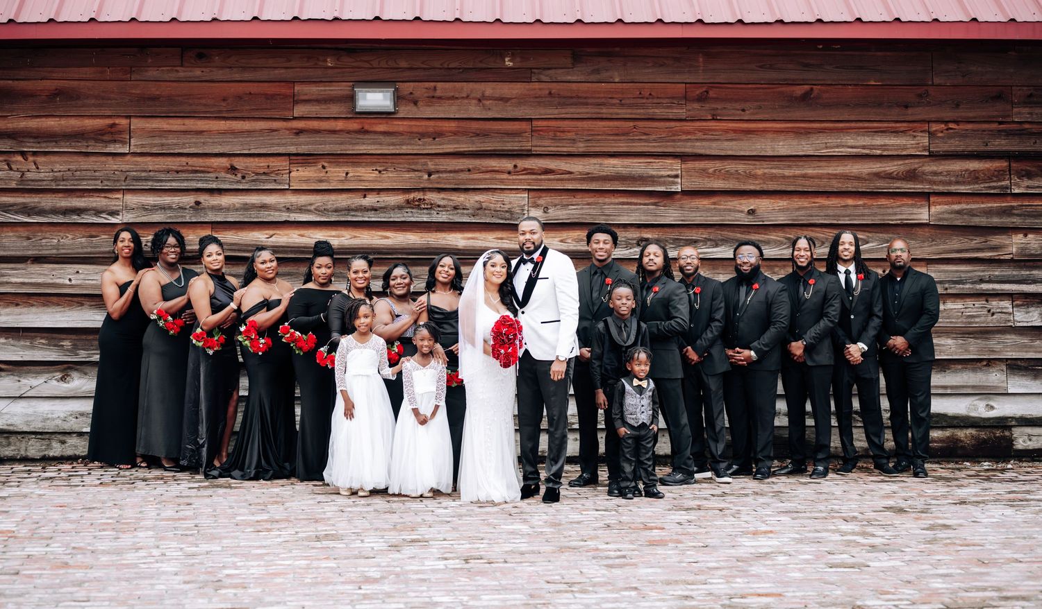 Wedding party members sit on rustic wooden steps in coordinated formal attire for group photos.
