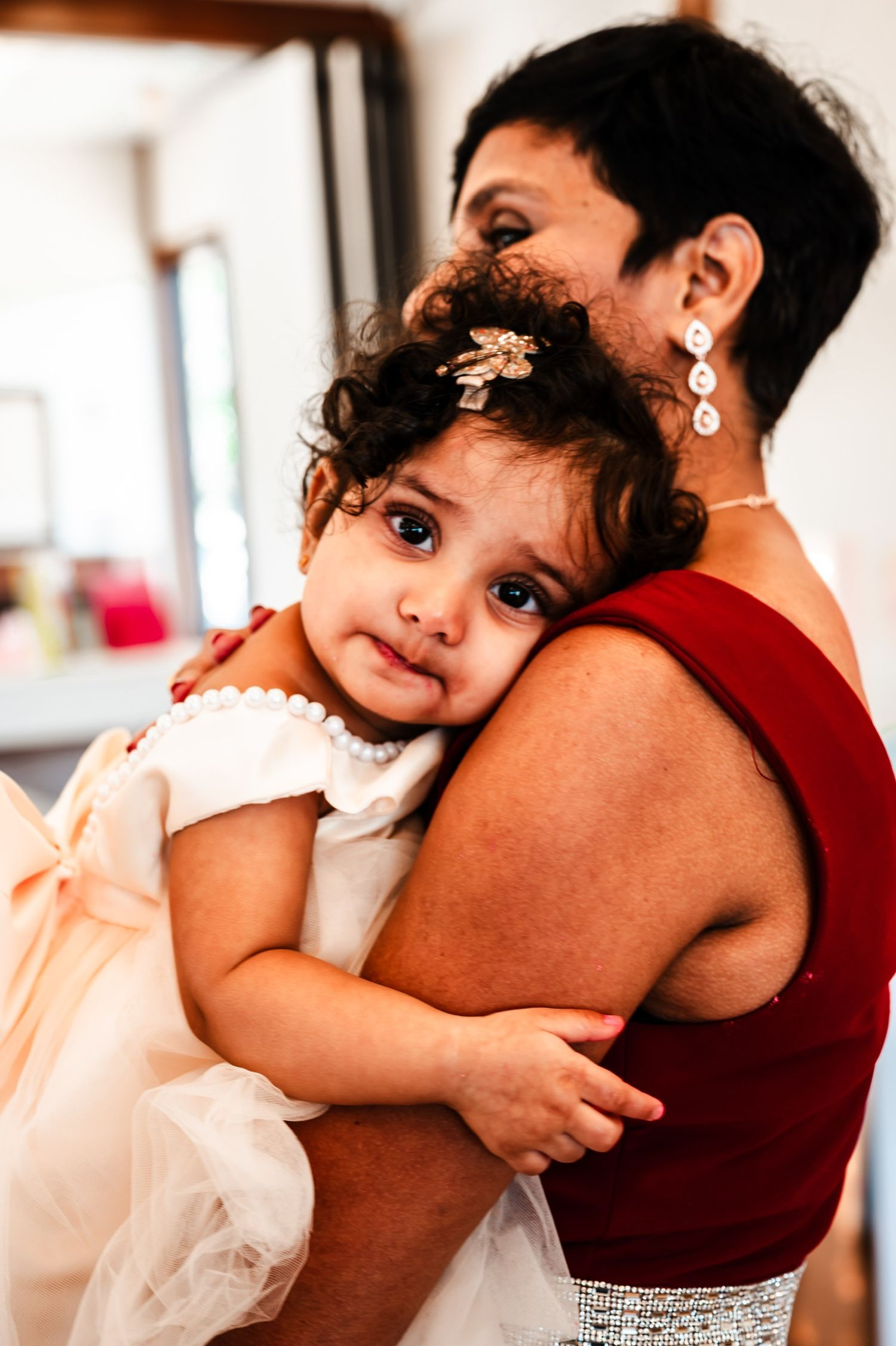 Baby in white dress snuggles close during an intimate portrait session.