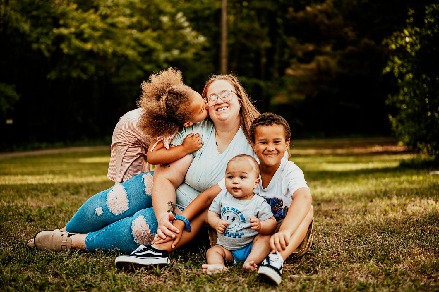 Family having fun together while relaxing on grass during sunset photo shoot.